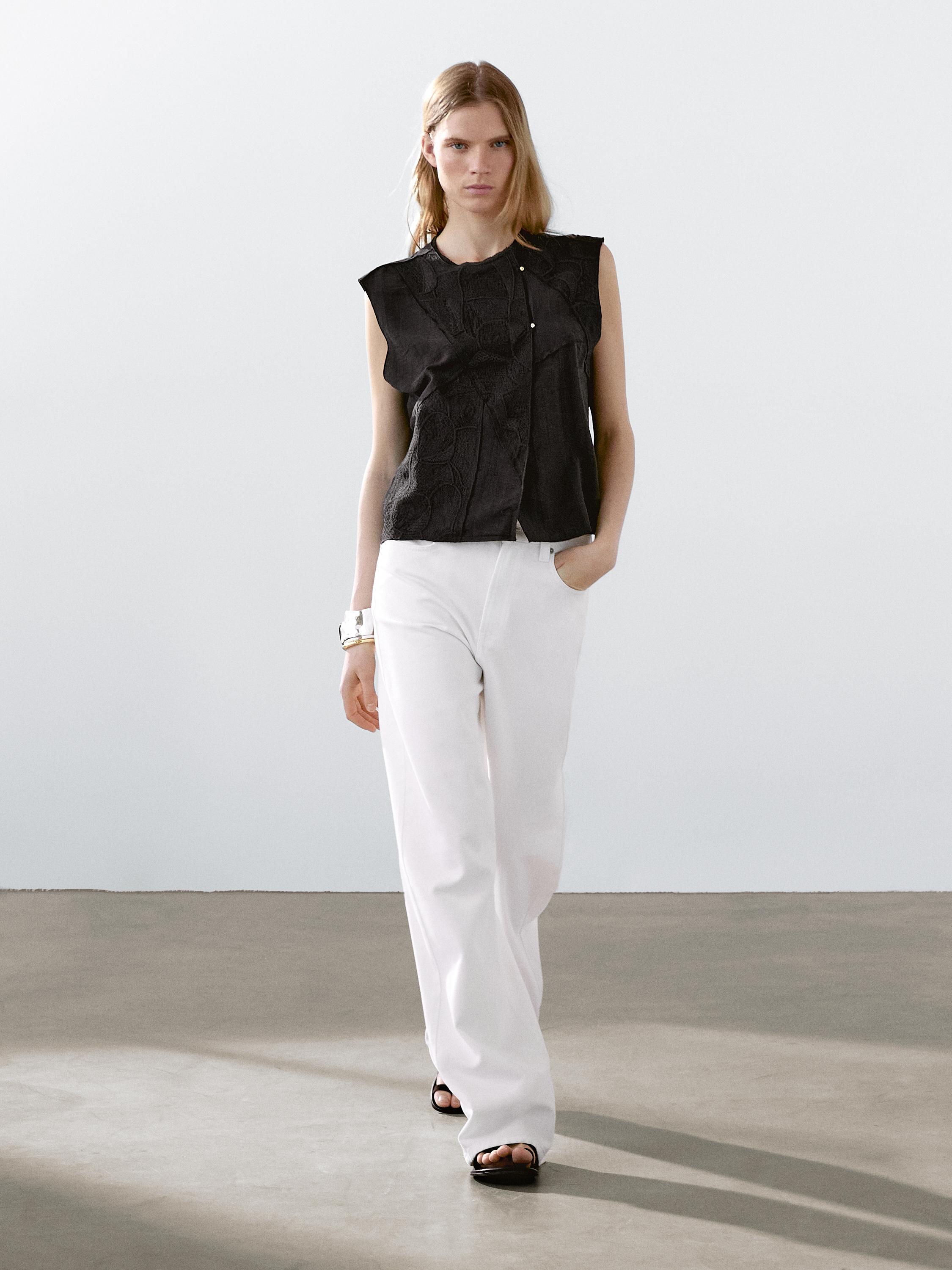 طقم صدرية سوداء بدون أكمام وبنطلون أبيض واسع.