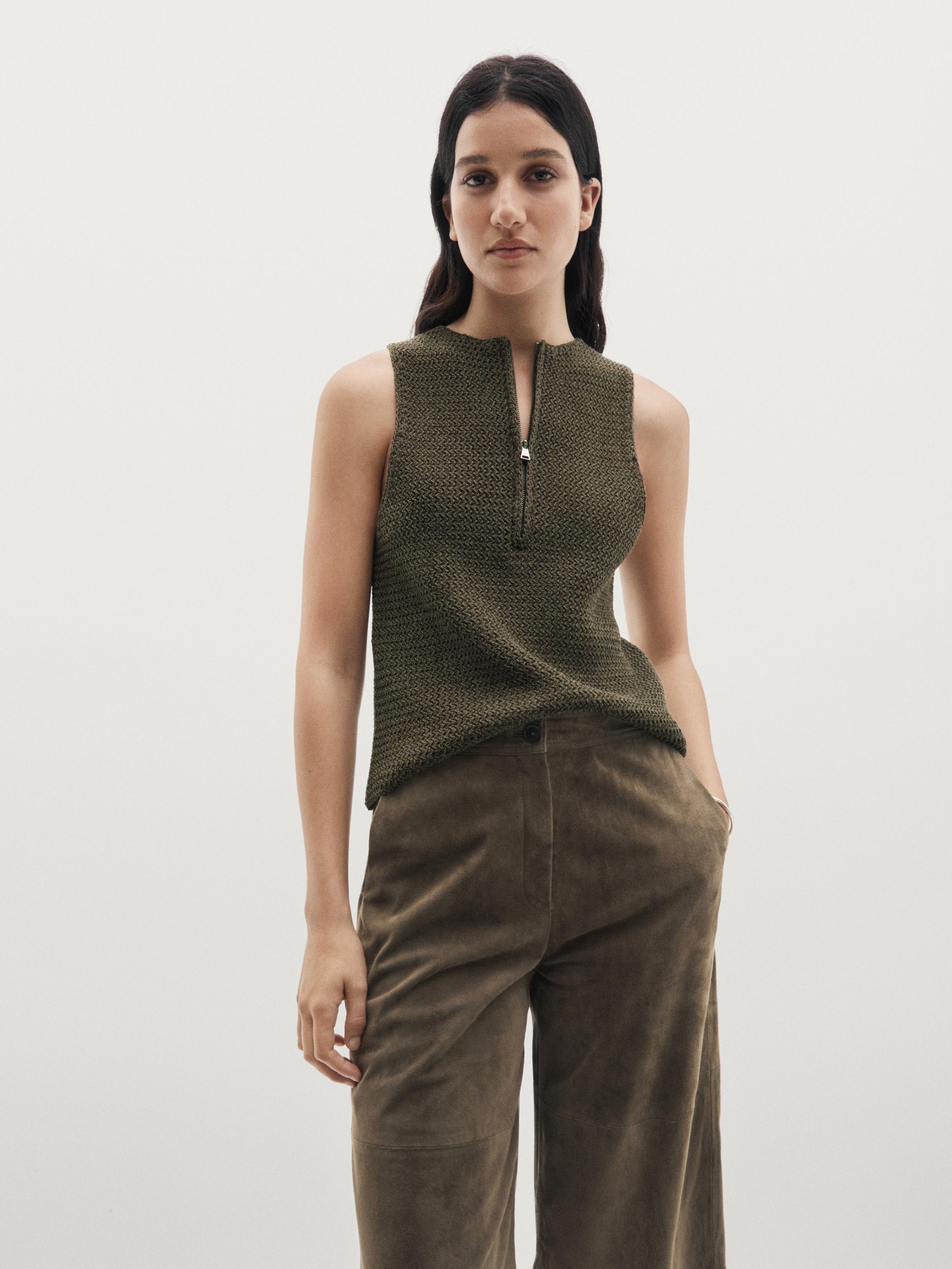 Conjunto de top café sin mangas con cierre frontal y pantalones cafés con bolsillos laterales.