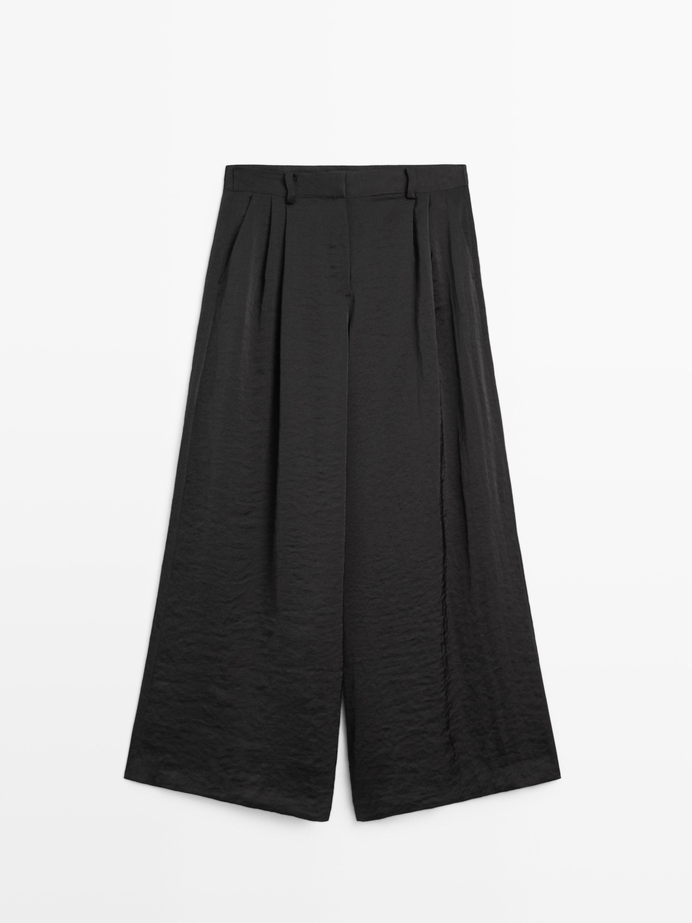 Vista frontal de pantalón ancho negro con pinzas y pretina con trabillas.