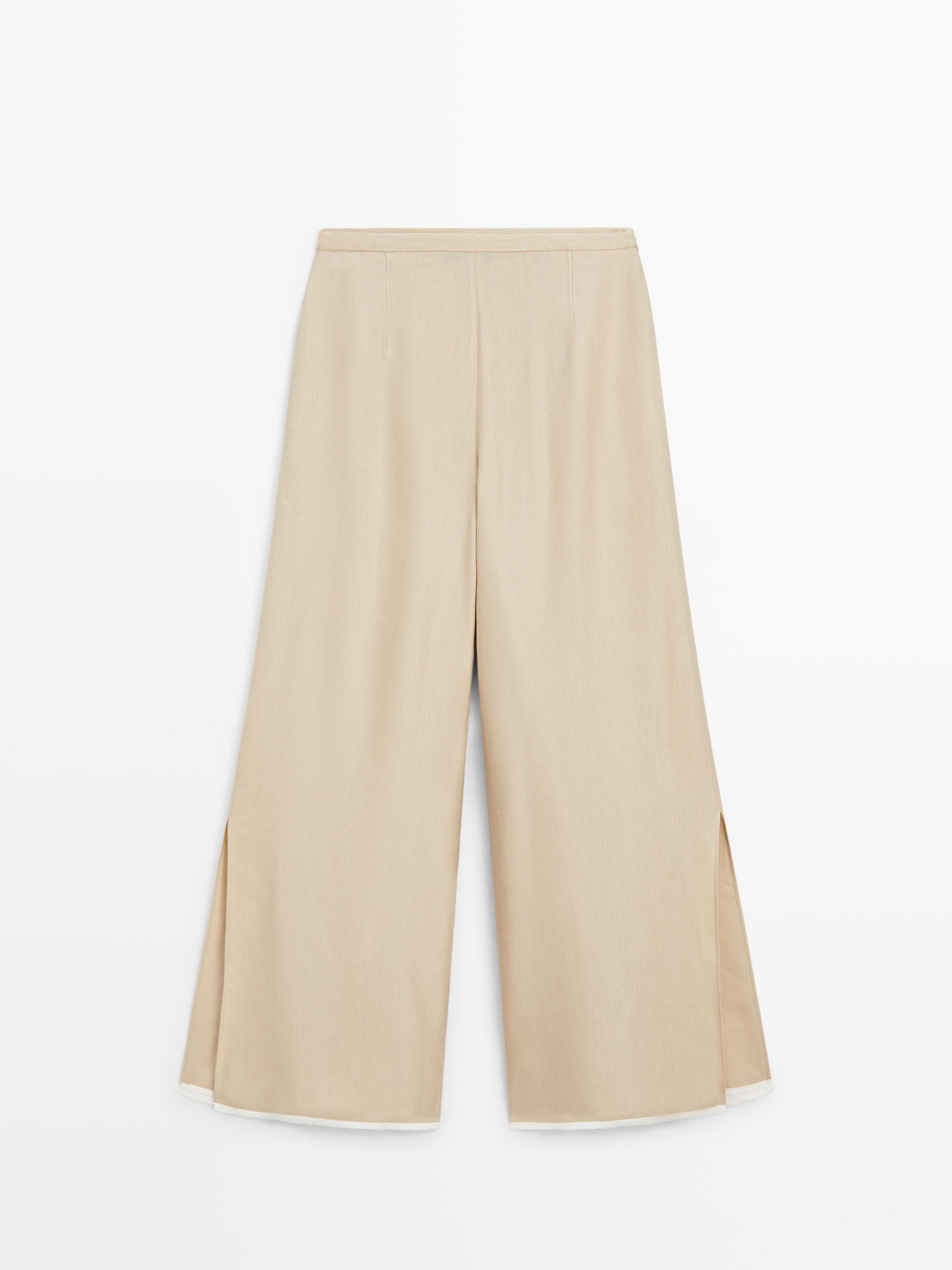 Yanları yırtmaçlı, bej renkli, geniş paça pantolonun önden görünümü.