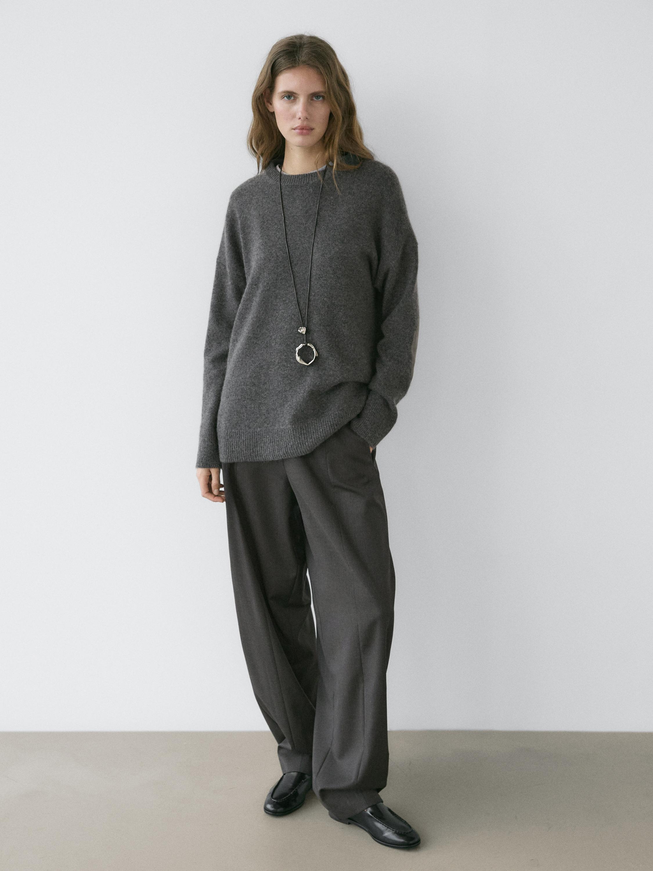 Orta gri oversize, dirsek yamalı süveter ve koyu renk bol paça pantolon takımı.