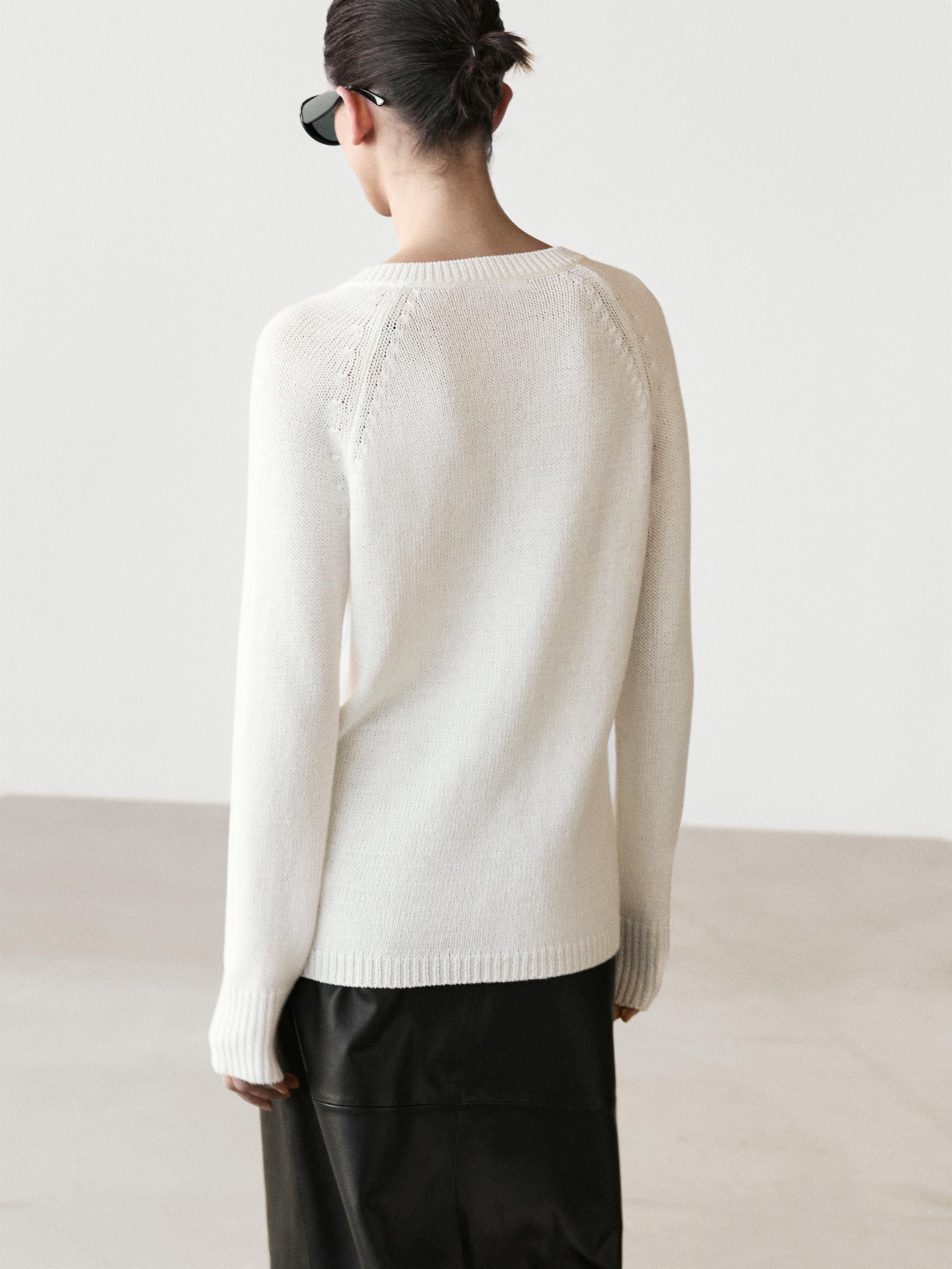 Conjunto aus weißem Strick-Jersey mit Rundhalsausschnitt und langen Ärmeln, von hinten gesehen.