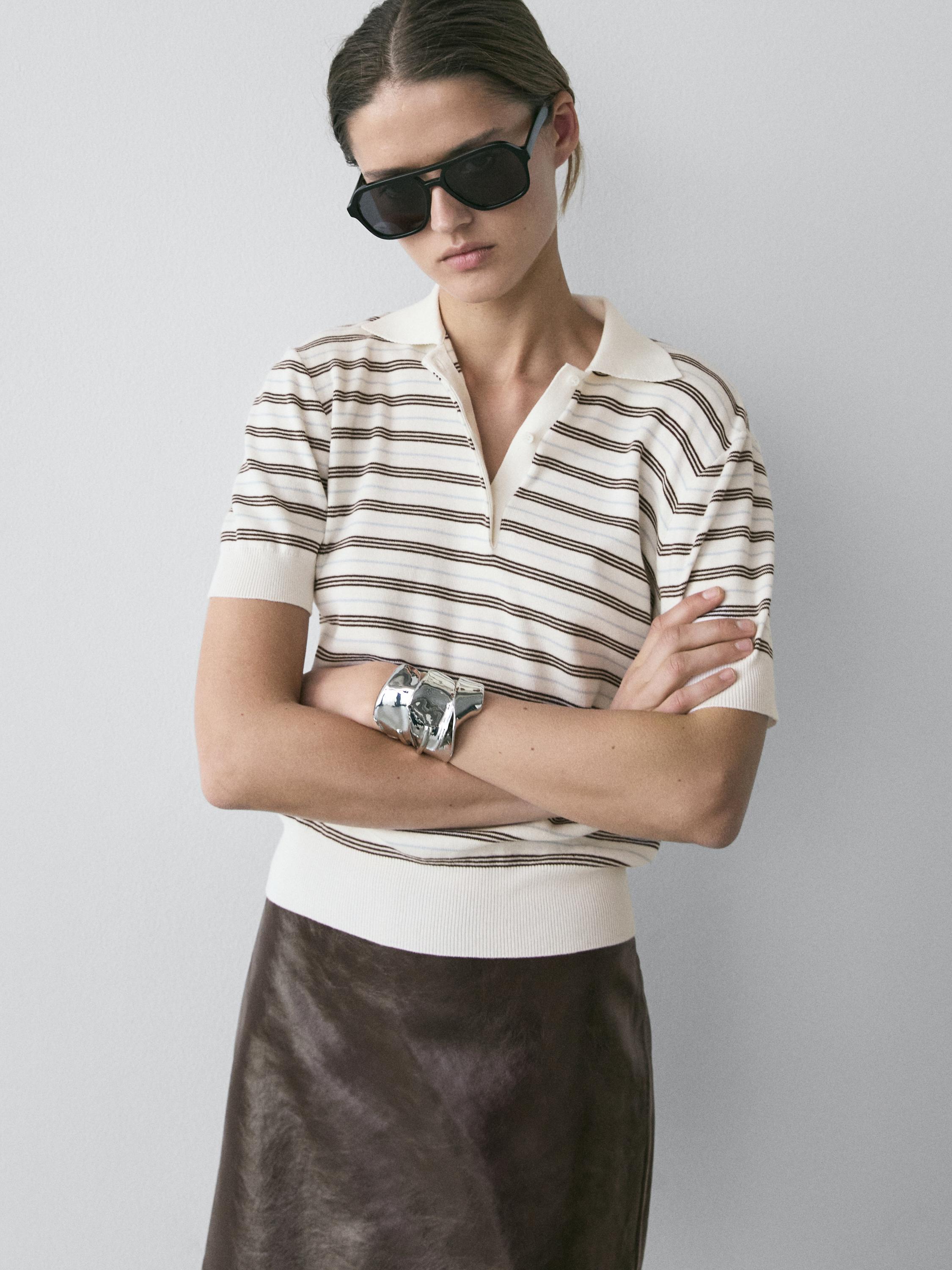 Plano medio de polo crudo a rayas marrones, manga corta, cuello clásico, con falda marrón visible.