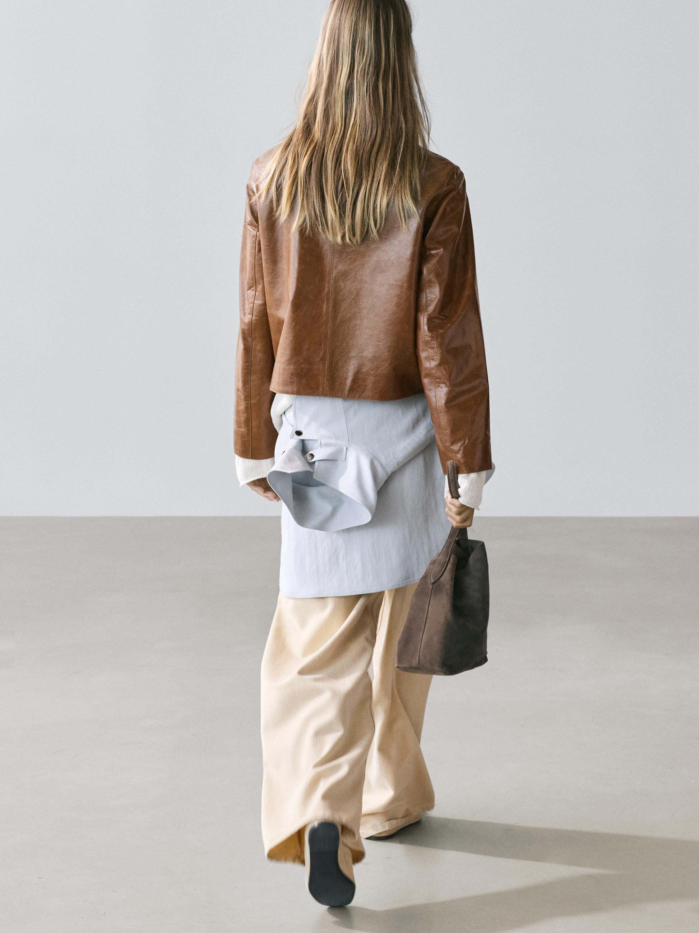 Camel koloreko bomber jaka, alkandora luze zuria eta praka zabal beixak.