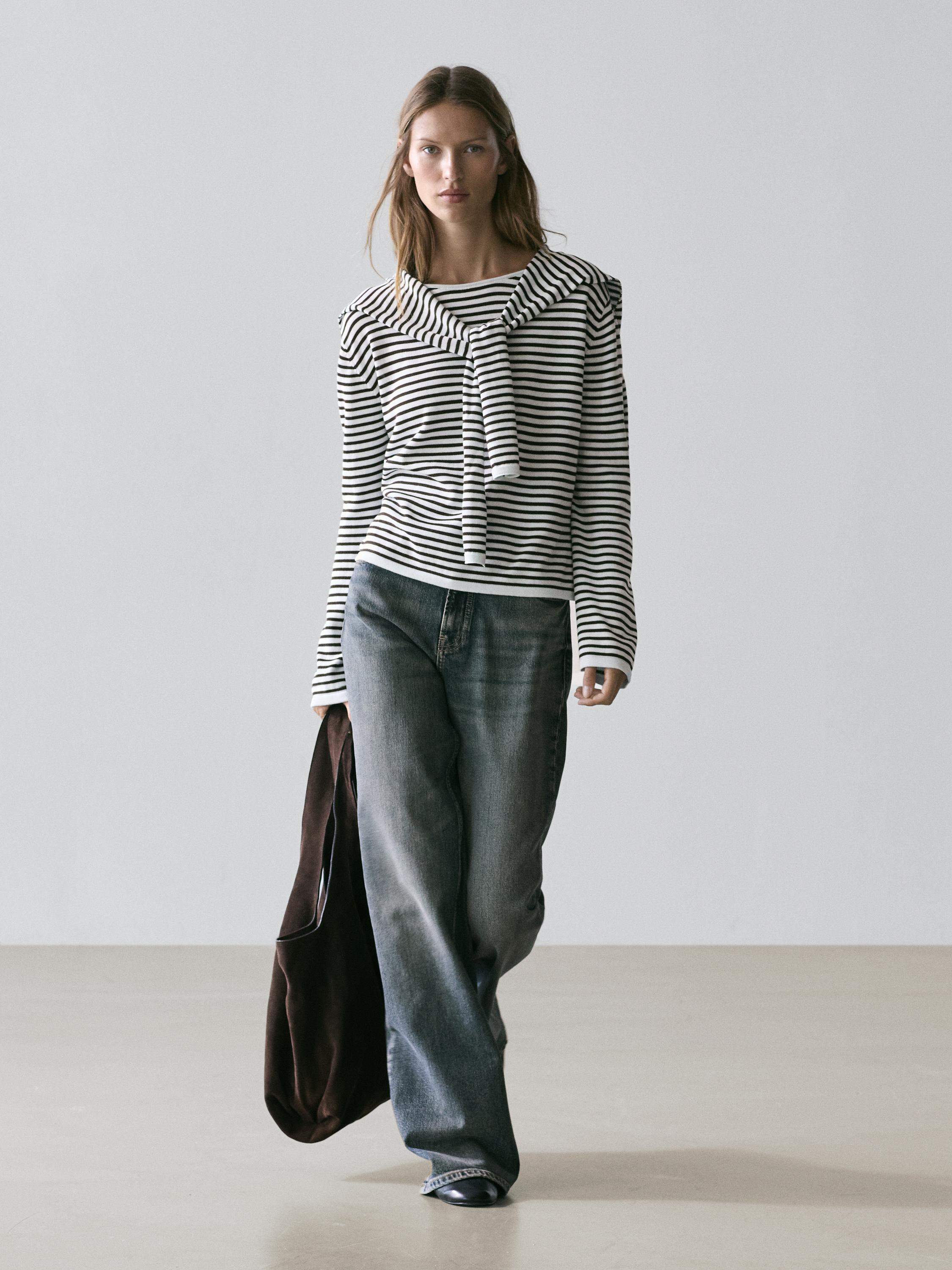 Black and white striped sweater set with sleeve detail and dark blue wide-leg jeans.