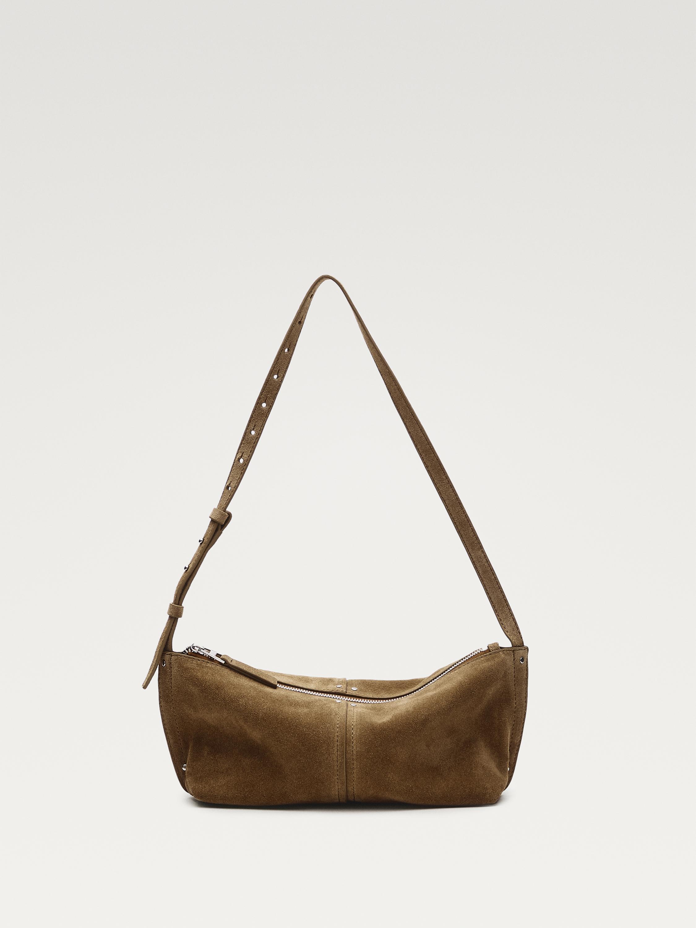 Front view of a sand-colored handbag with an adjustable strap and a top zipper closure.