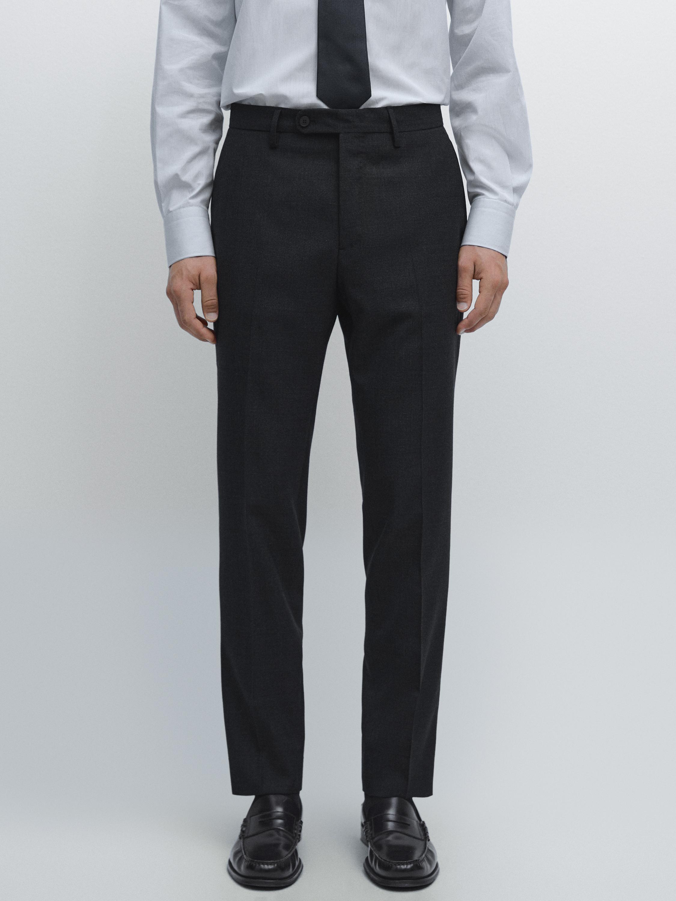 Ensemble composé d'un pantalon de costume bleu marine avec des poches latérales et une fermeture boutonnée, d'une chemise blanche et d'une cravate noire.