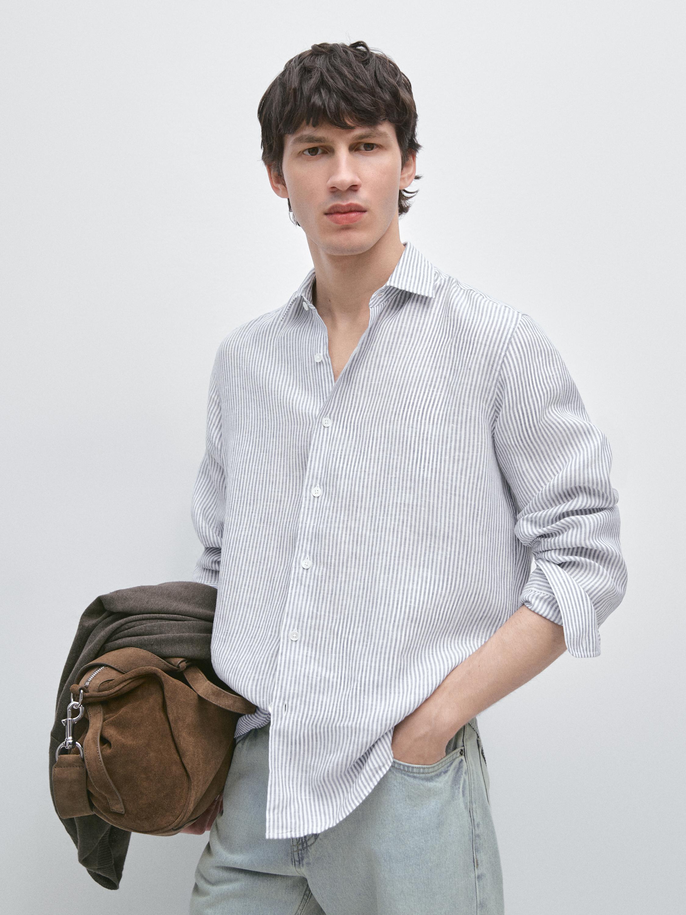 Ensemble chemise bleue à rayures verticales avec manches longues et boutons visibles, combinée à un pantalon clair.