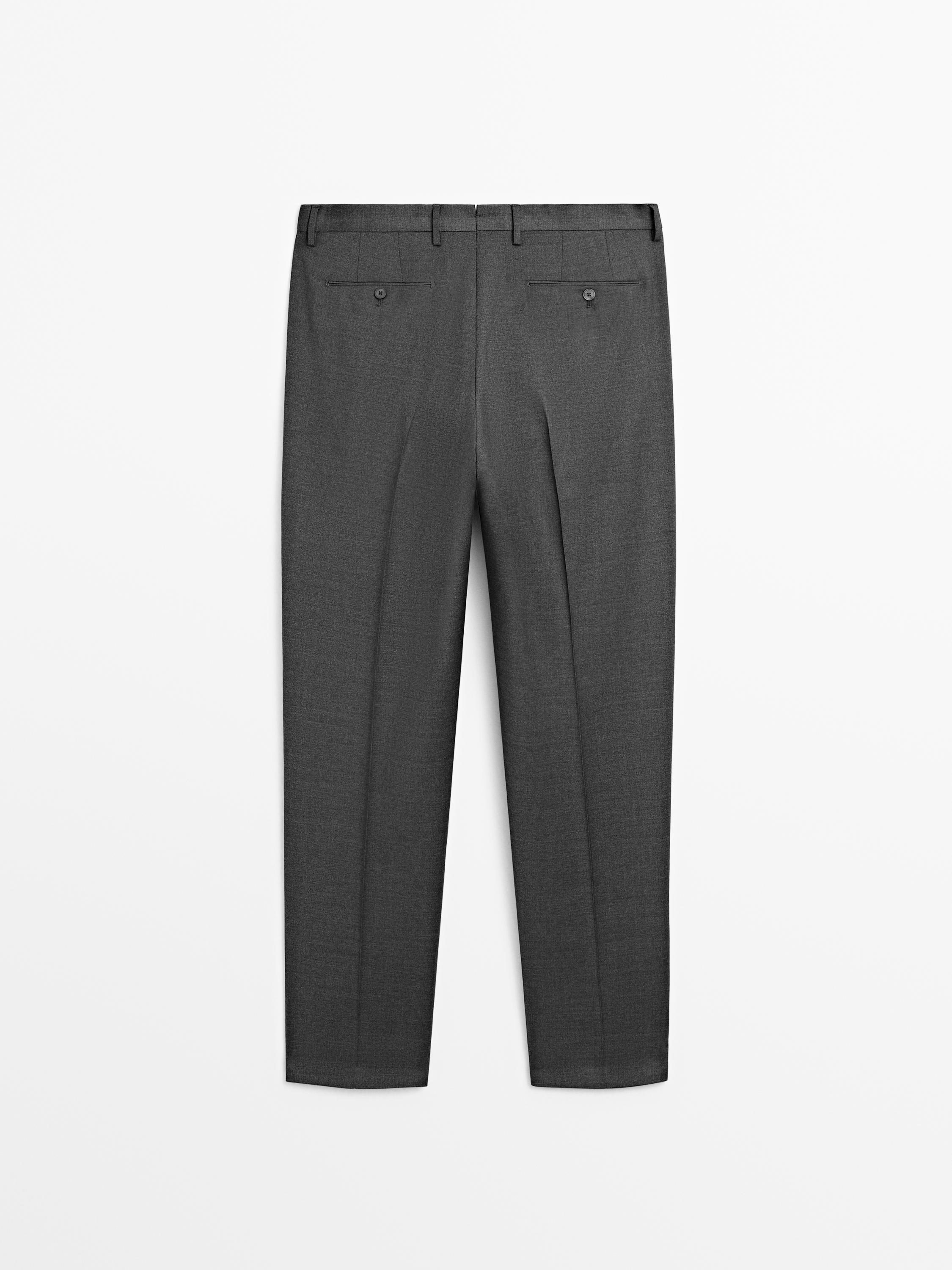 Rear view of gray suit pants with flap and button back pockets.