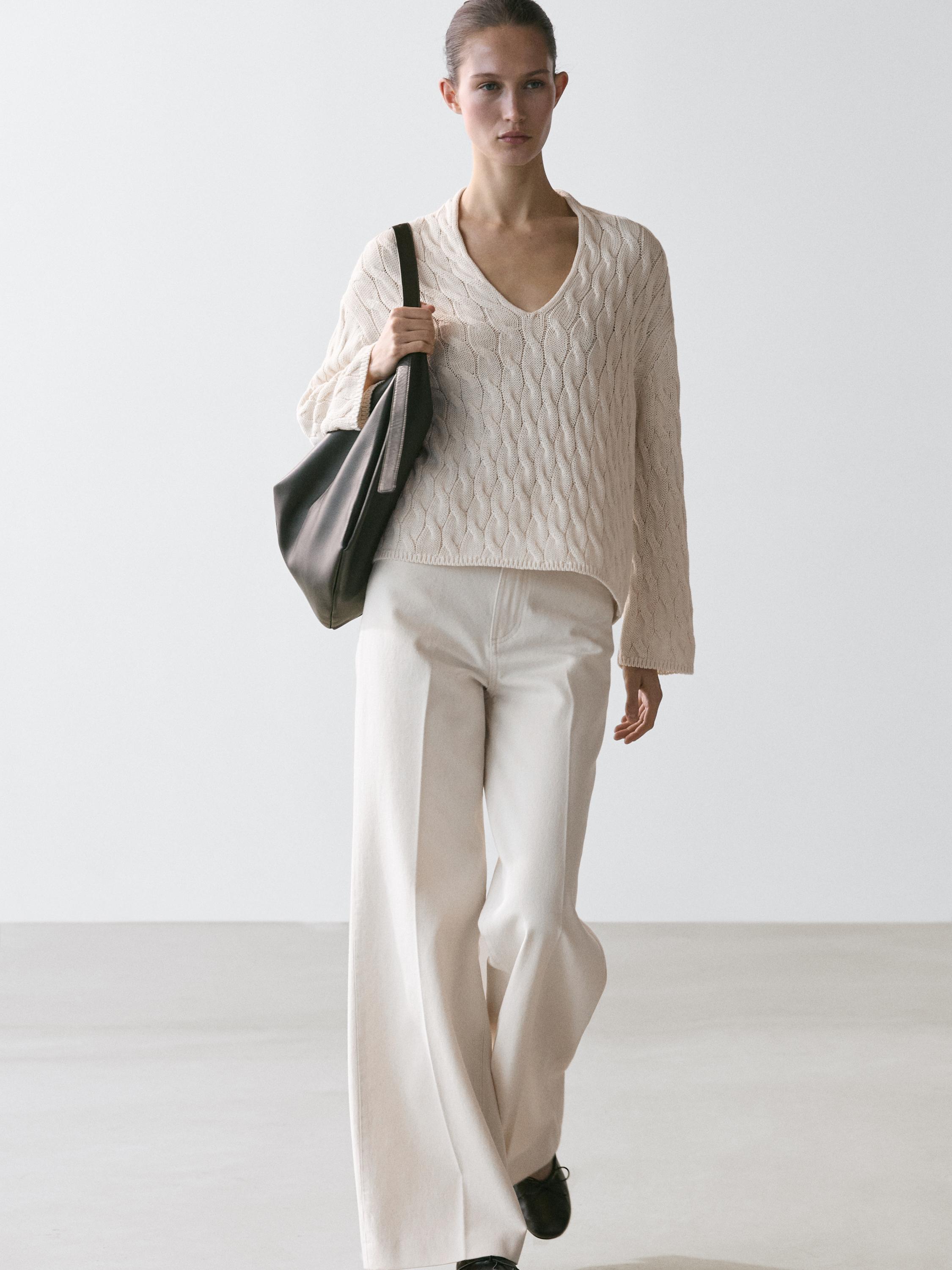 Conxunto de xersei cru con detalle de nós e pantalóns anchos a xogo.