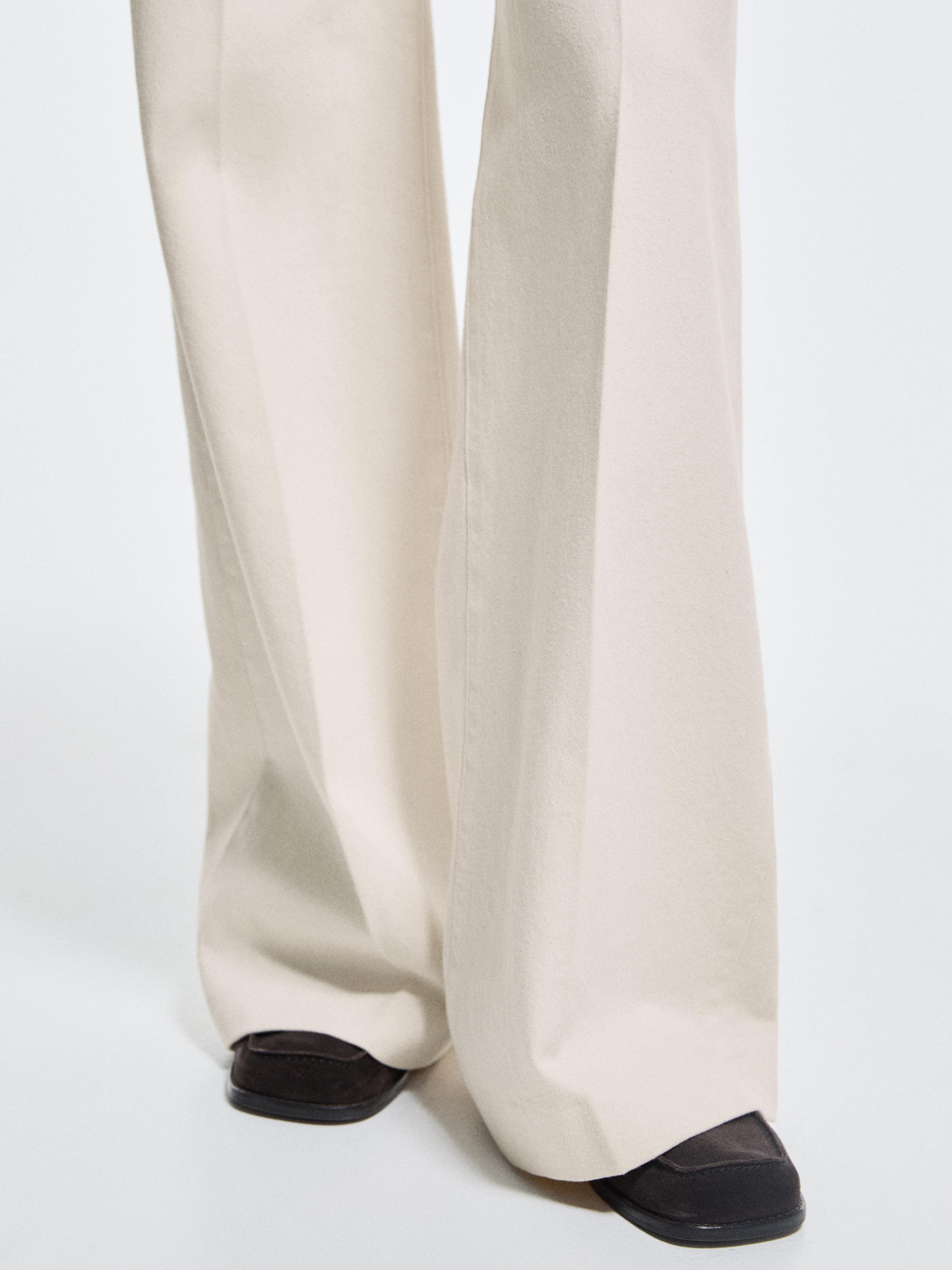 Plano medio de pantalones palazzo crudos, tiro alto, con pernera ancha y caída recta.