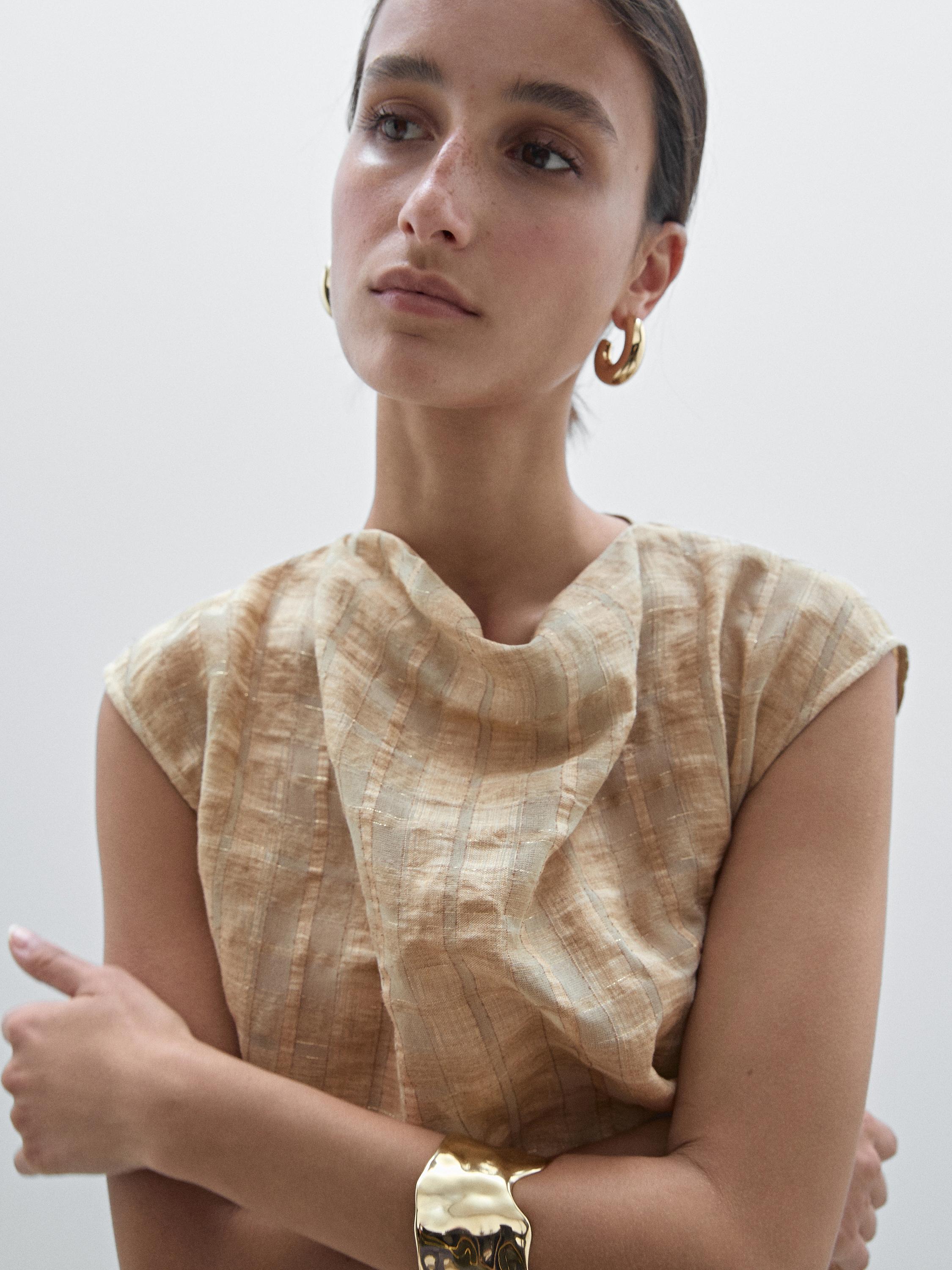 لقطة متوسطة لبلوزة بيج منقوشة بأكمام قصيرة.