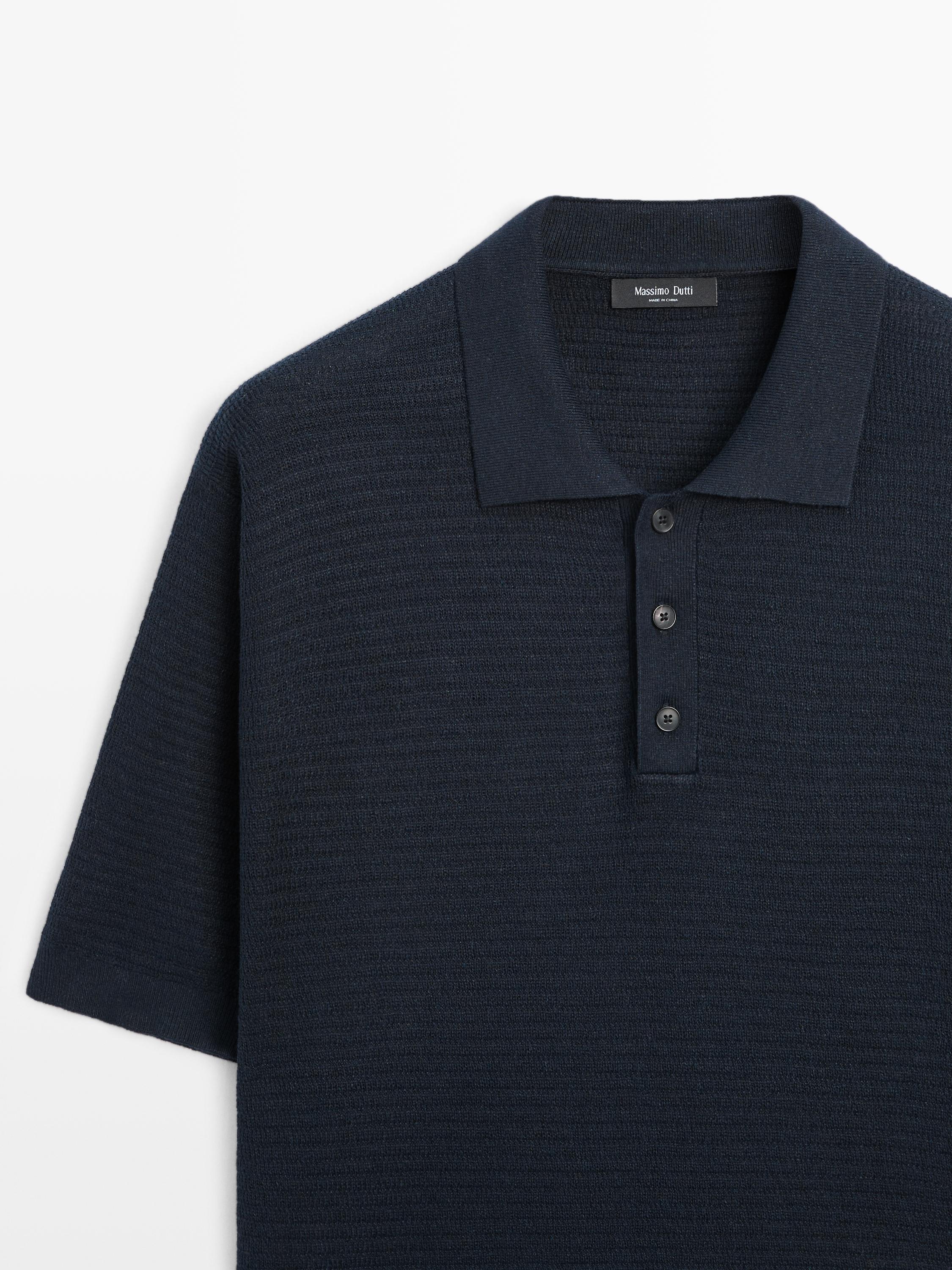 "Plano medio de polo azul marino de punto con mangas cortas y botonadura frontal de tres botones."