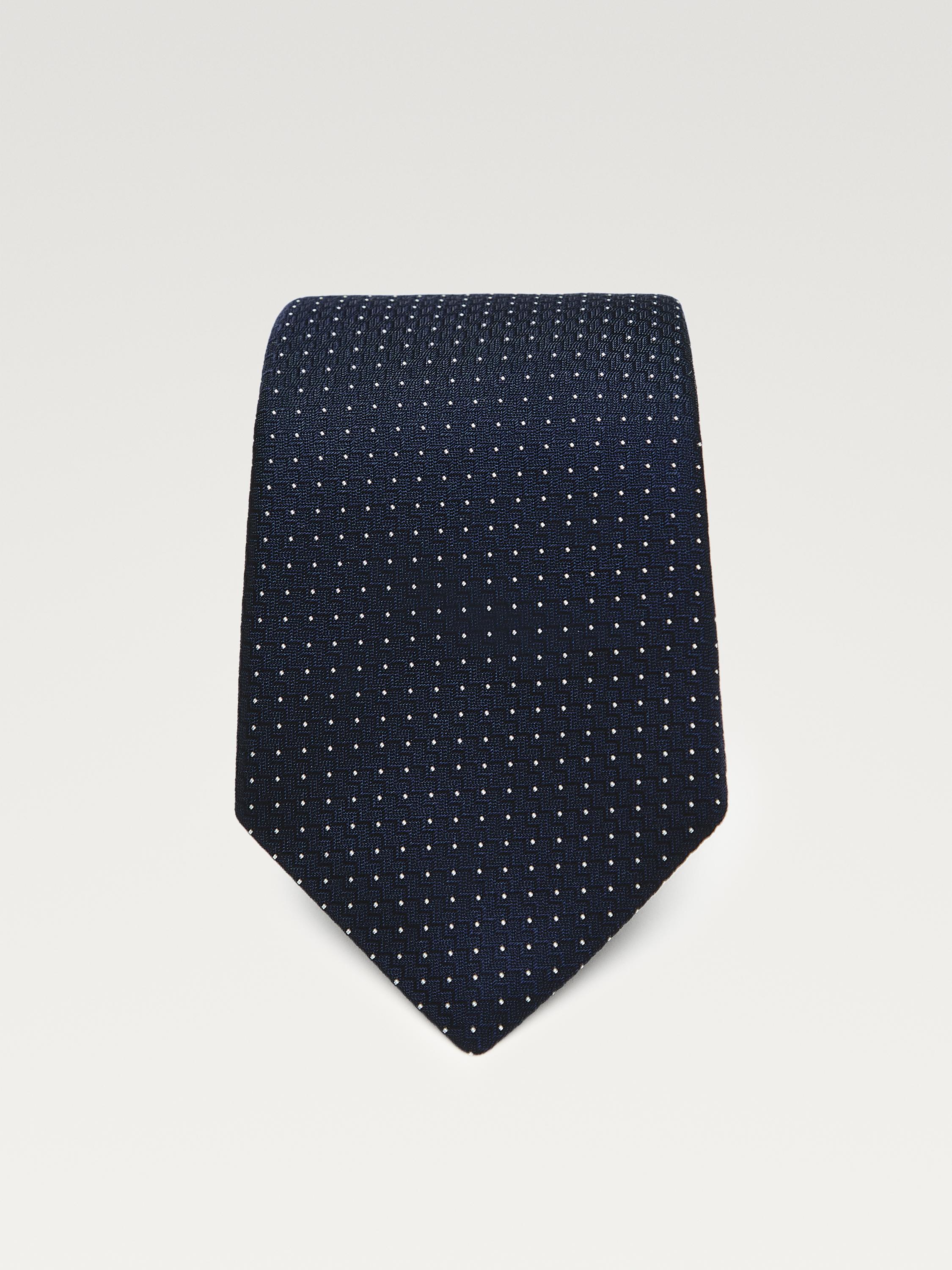 Front view of a navy blue tie with white polka dots.