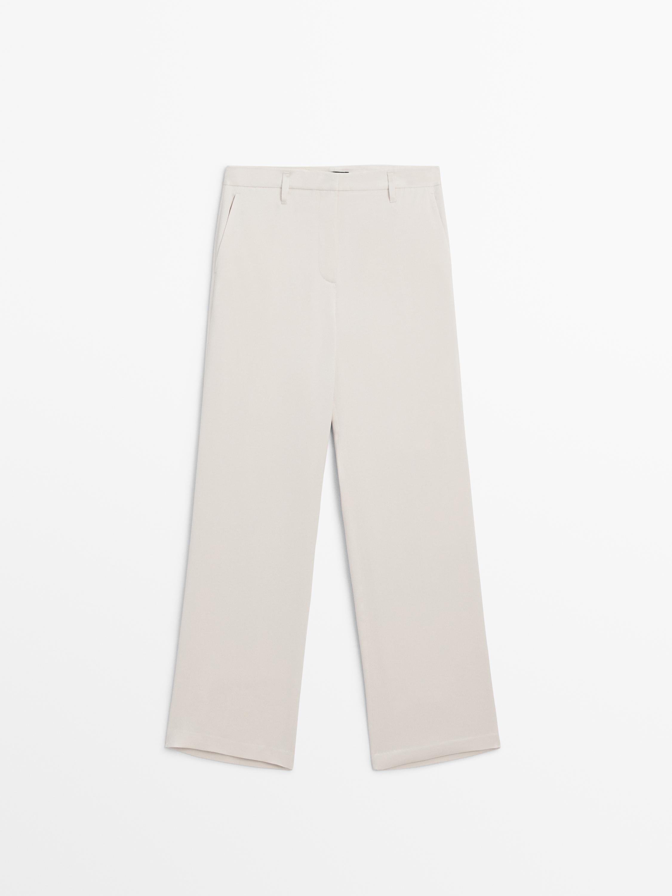 Vue de face d'un pantalon beige avec poches latérales et fermeture dissimulée.