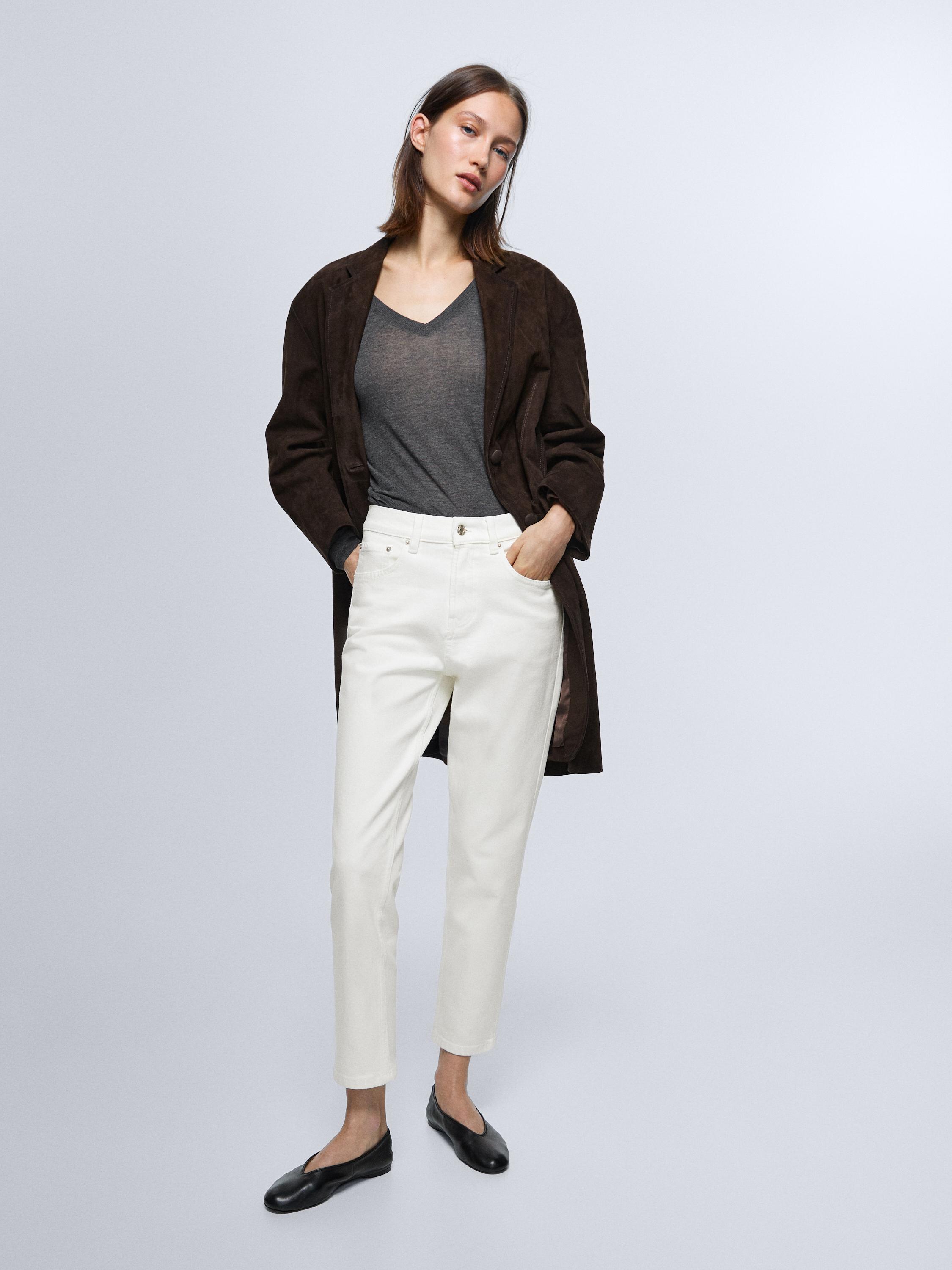 Conxunto de jeans branco roto slim fit de tiro medio, camiseta gris de colo en V e chaqueta marrón.