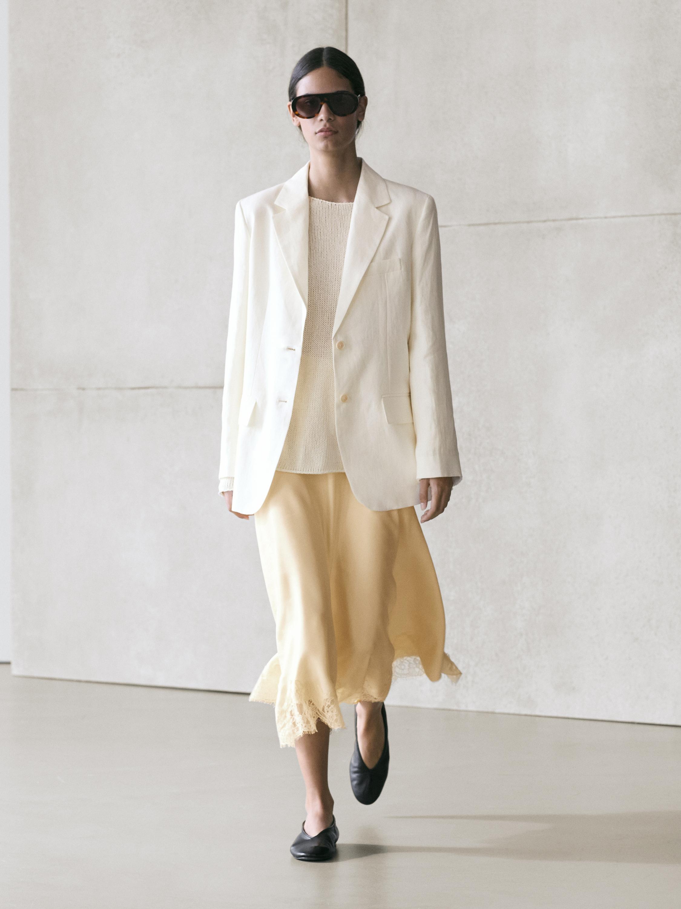 White blazer set, beige top, and asymmetrical vanilla skirt with lace detail on the hem.