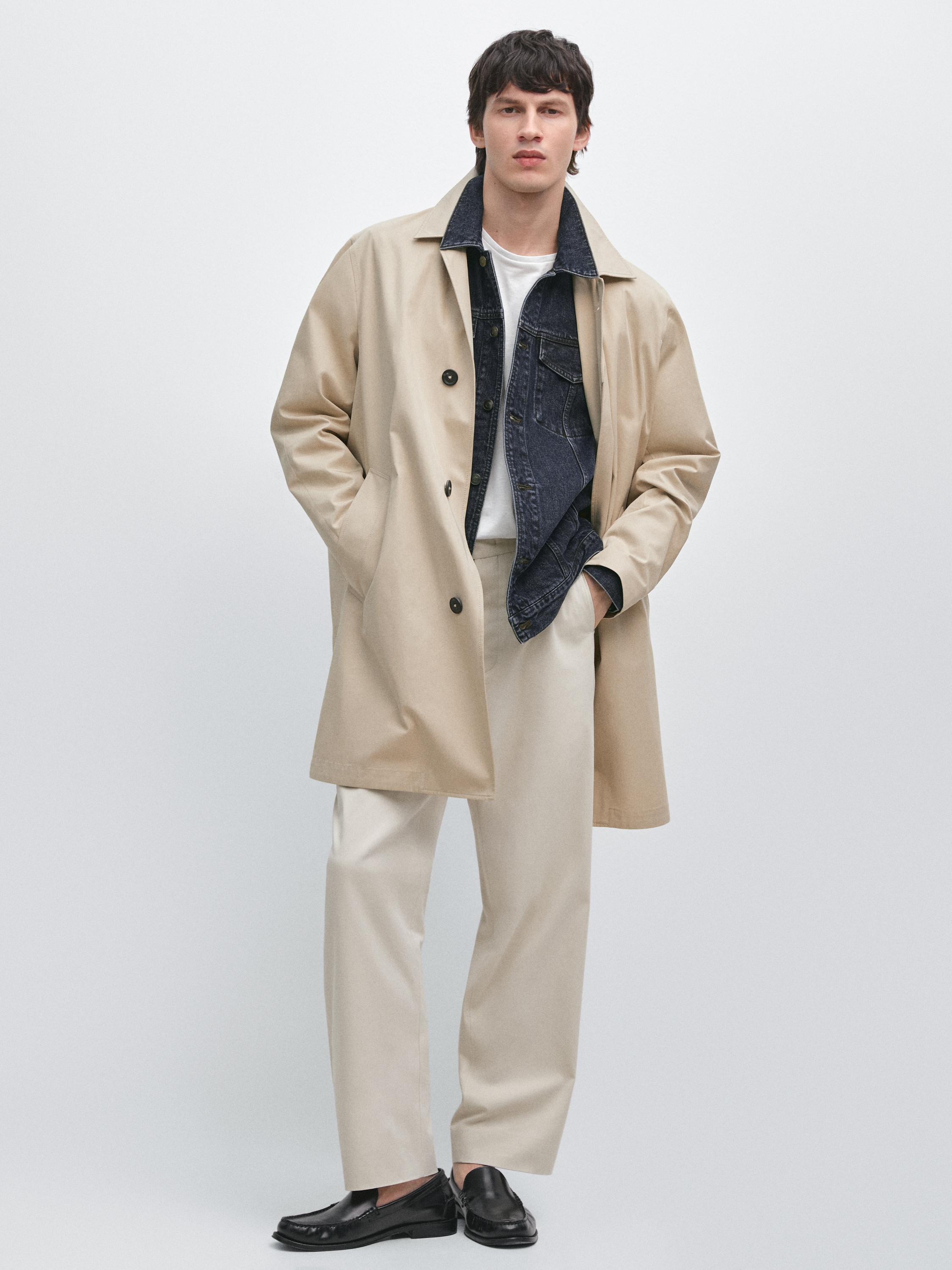 Conjunto de agasalho bege com botões, casaco de ganga azul, t-shirt branca, calças bege e mocassins pretos.