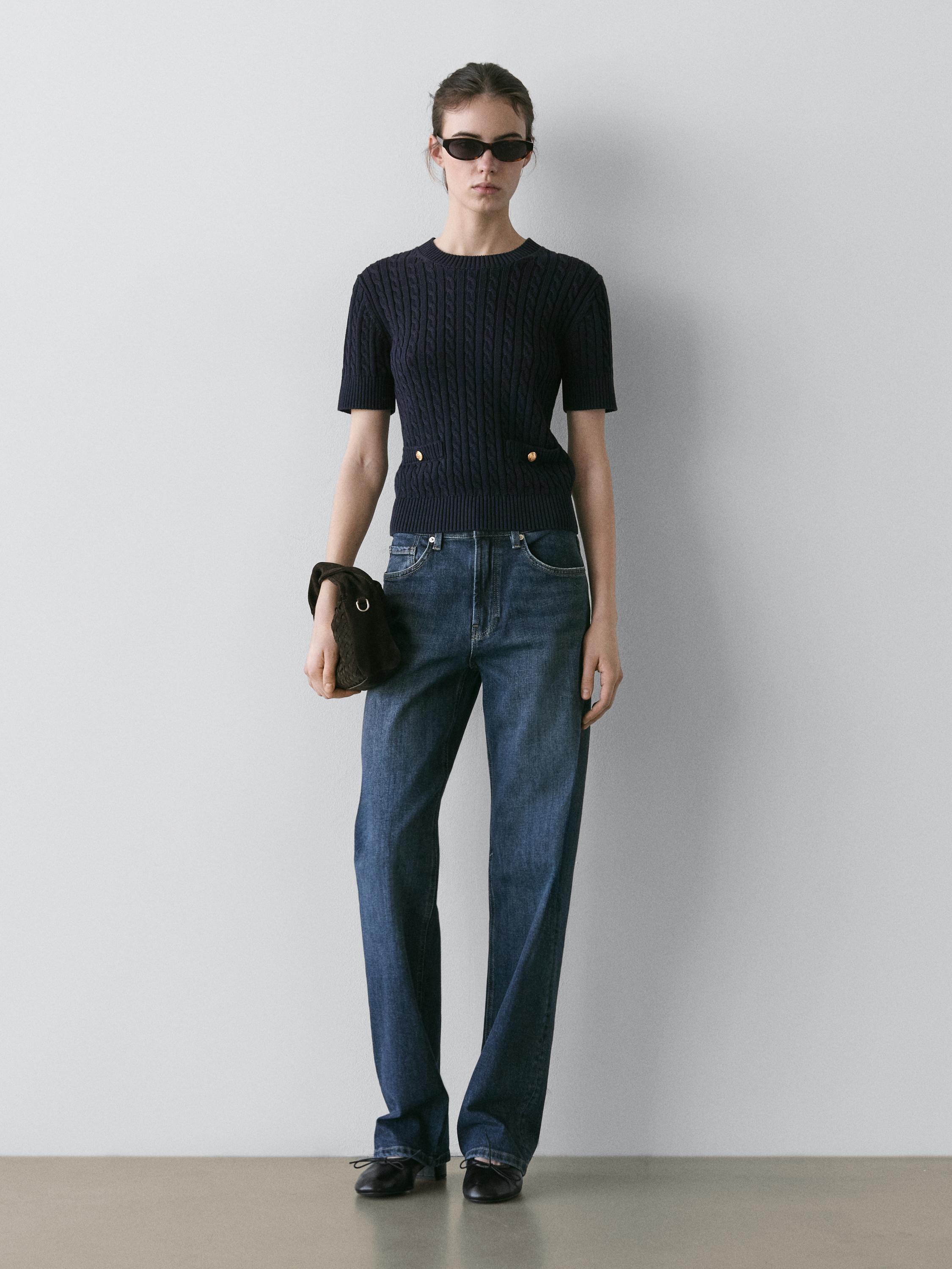 Navy blue cable knit sweater set with gold buttons and blue straight-leg jeans.