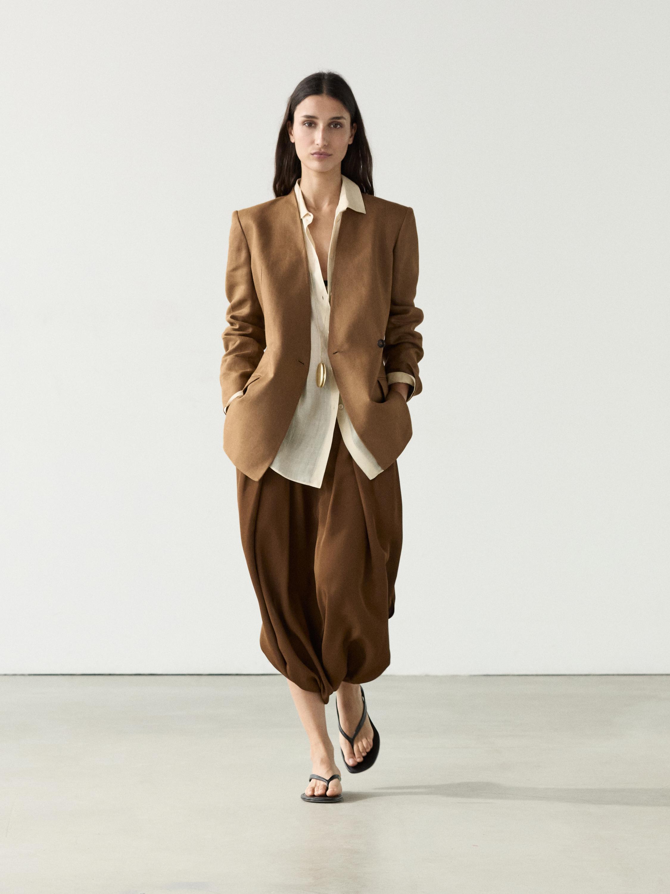 Conjunto de americana cruzada camel sin solapa, camisa blanca y pantalones marrones amplios.