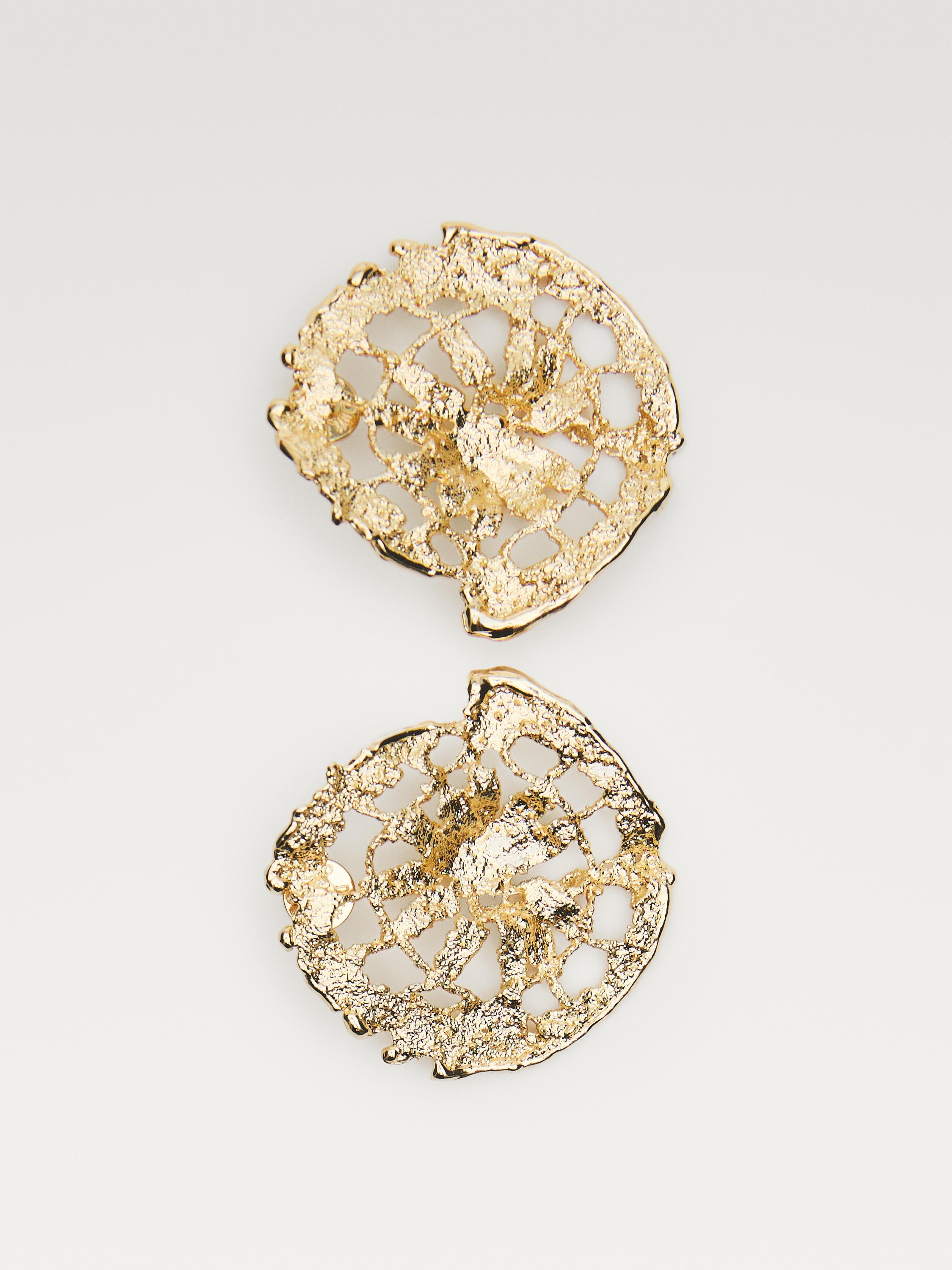 Boucles d'oreilles dorées avec texture irrégulière et motif ajouré circulaire.