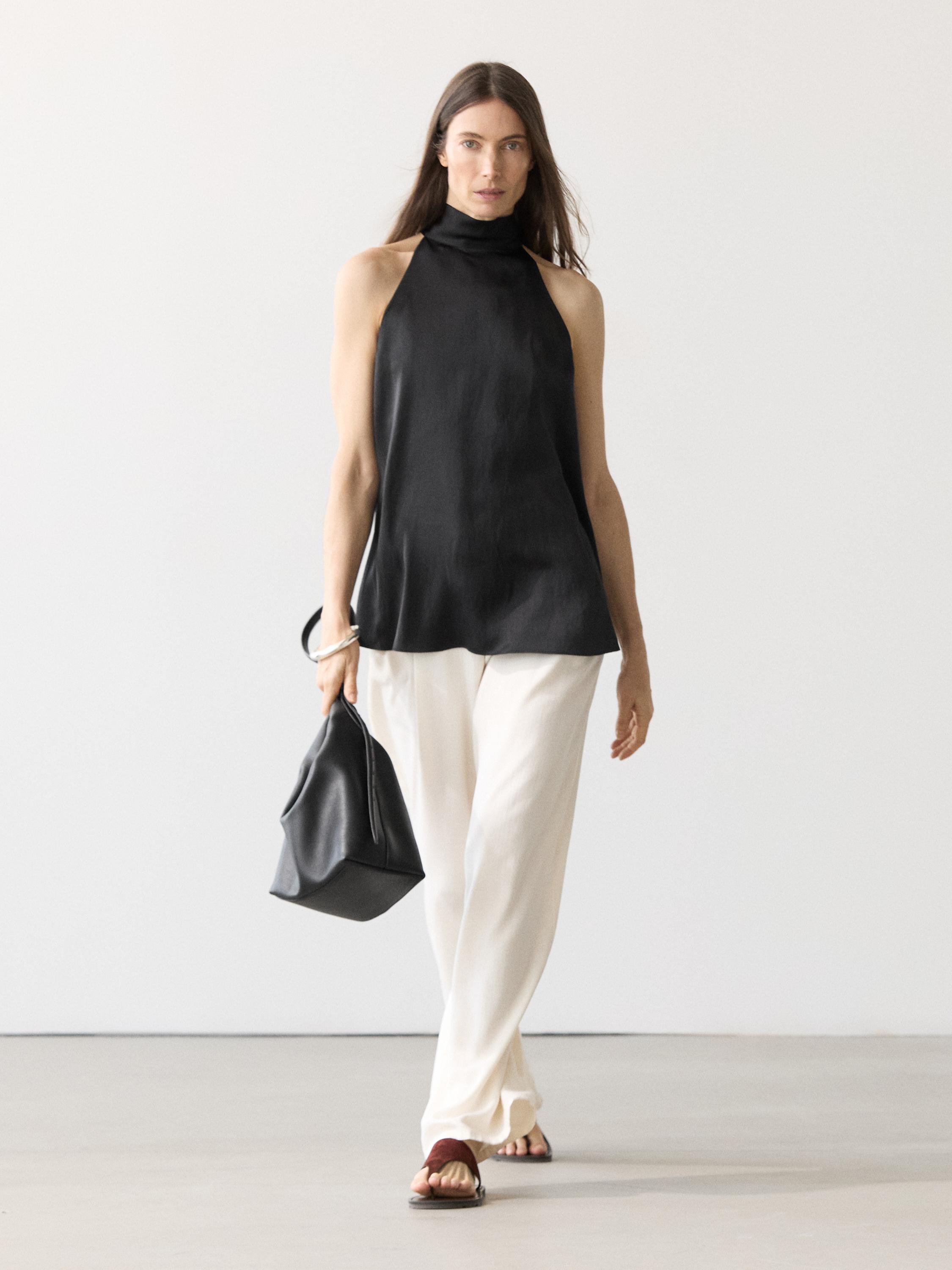 Ensemble top court dos nu satiné noir et pantalon ample blanc.