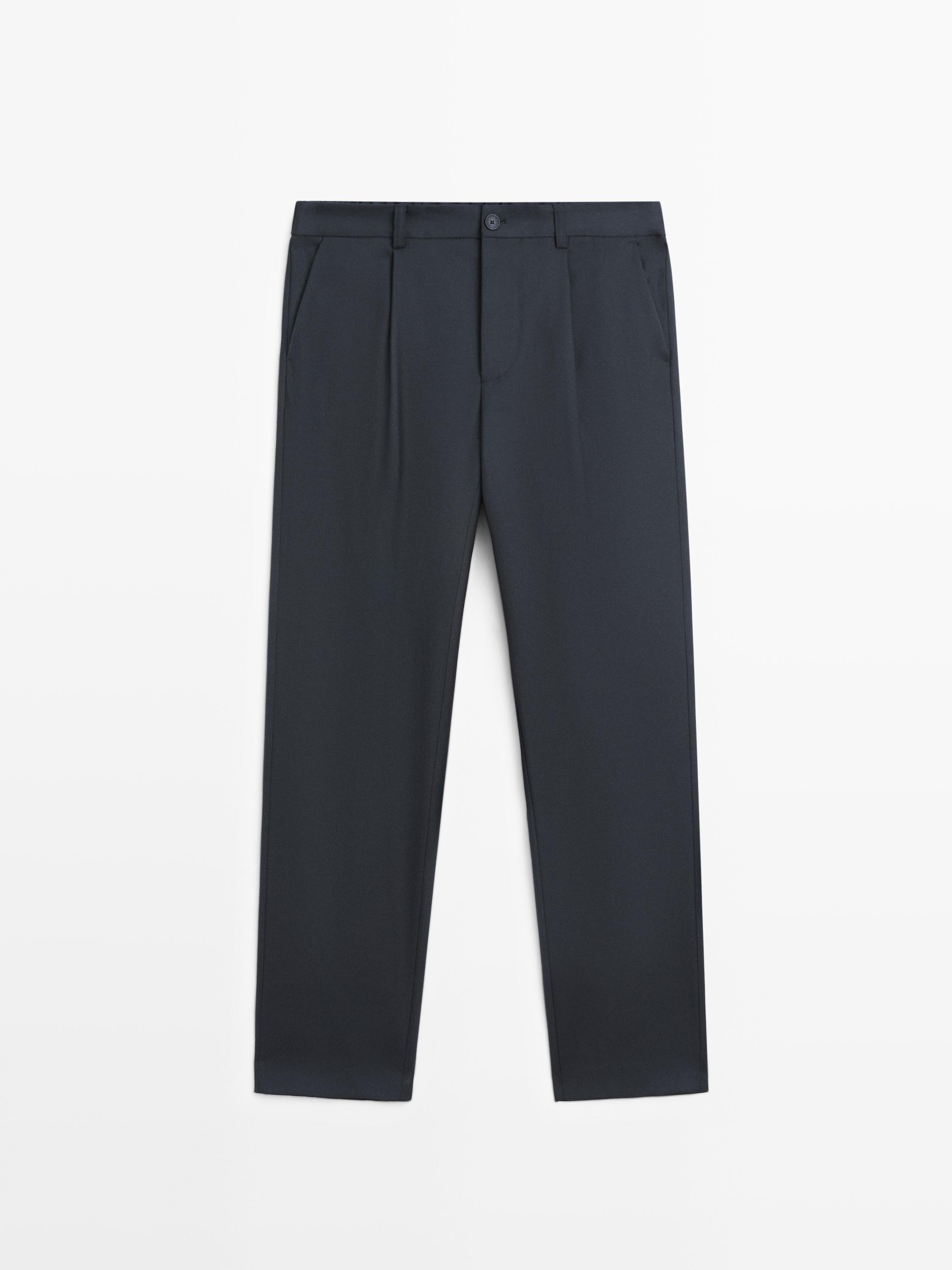 Front view of navy blue relaxed fit pants with pleats and side pockets.