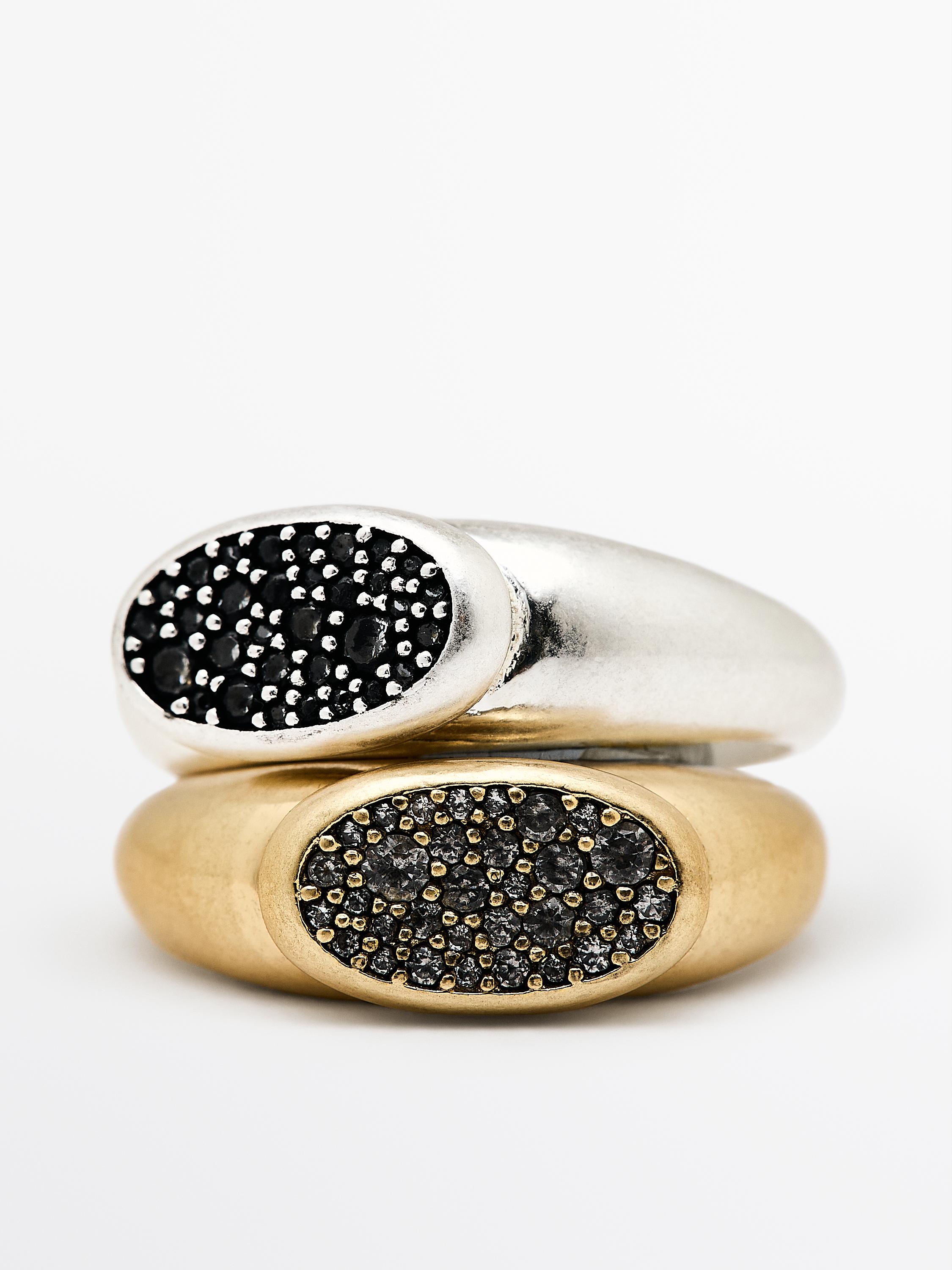 Set de dos anillos, uno dorado y otro plateado, con incrustaciones brillantes negras en la parte superior ovalada.