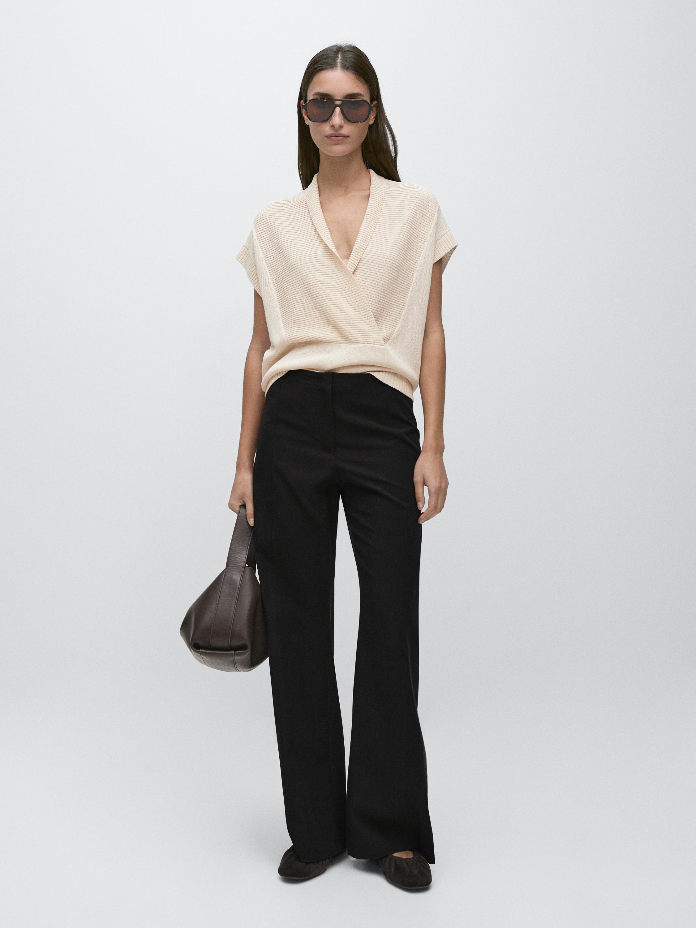 Conjunto de pantalón negro de corte flare y blusa beige de manga corta con escote en V.