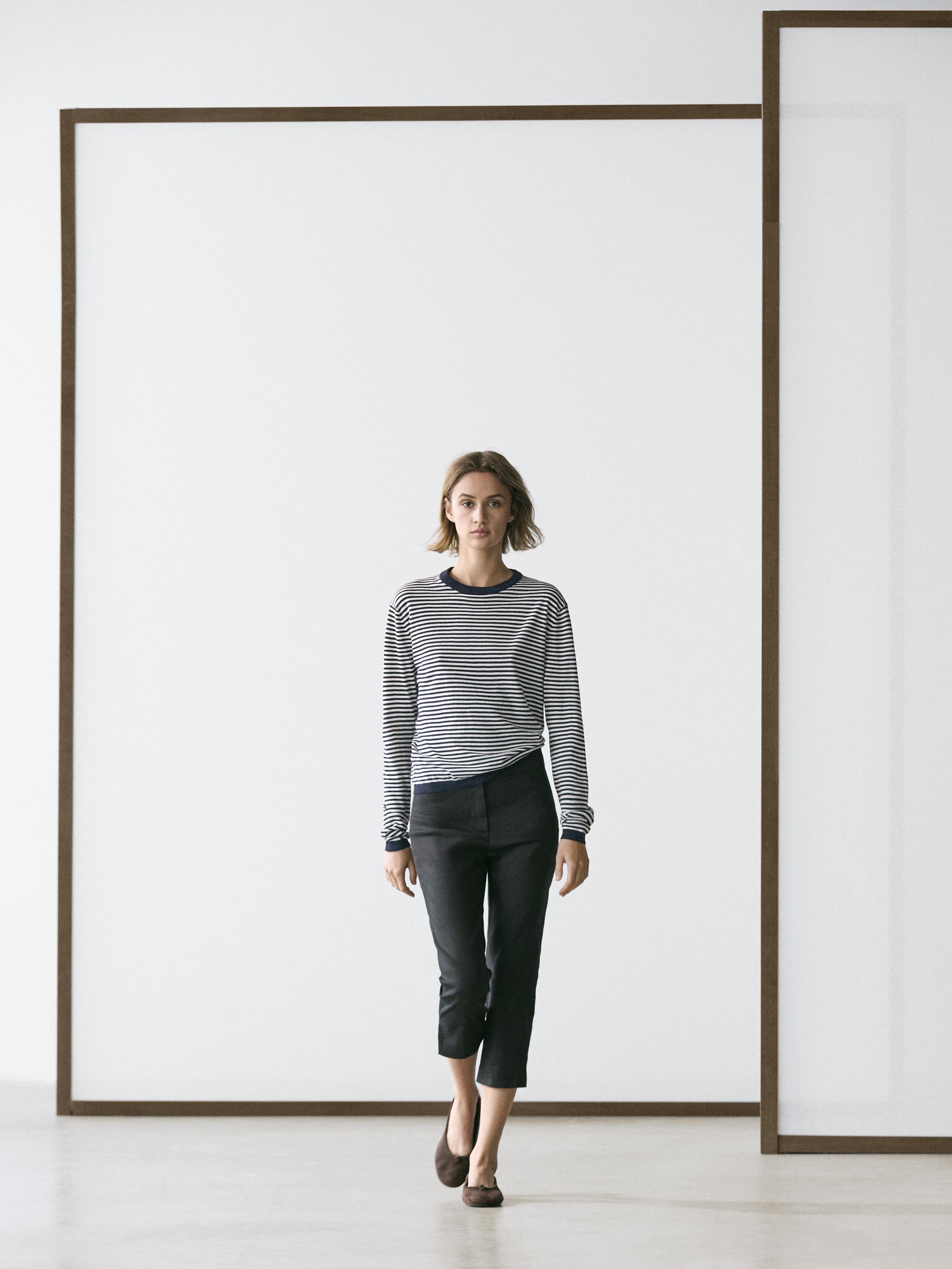 Conjunto de jersey de rayas azul marino y pantalones capri negros.