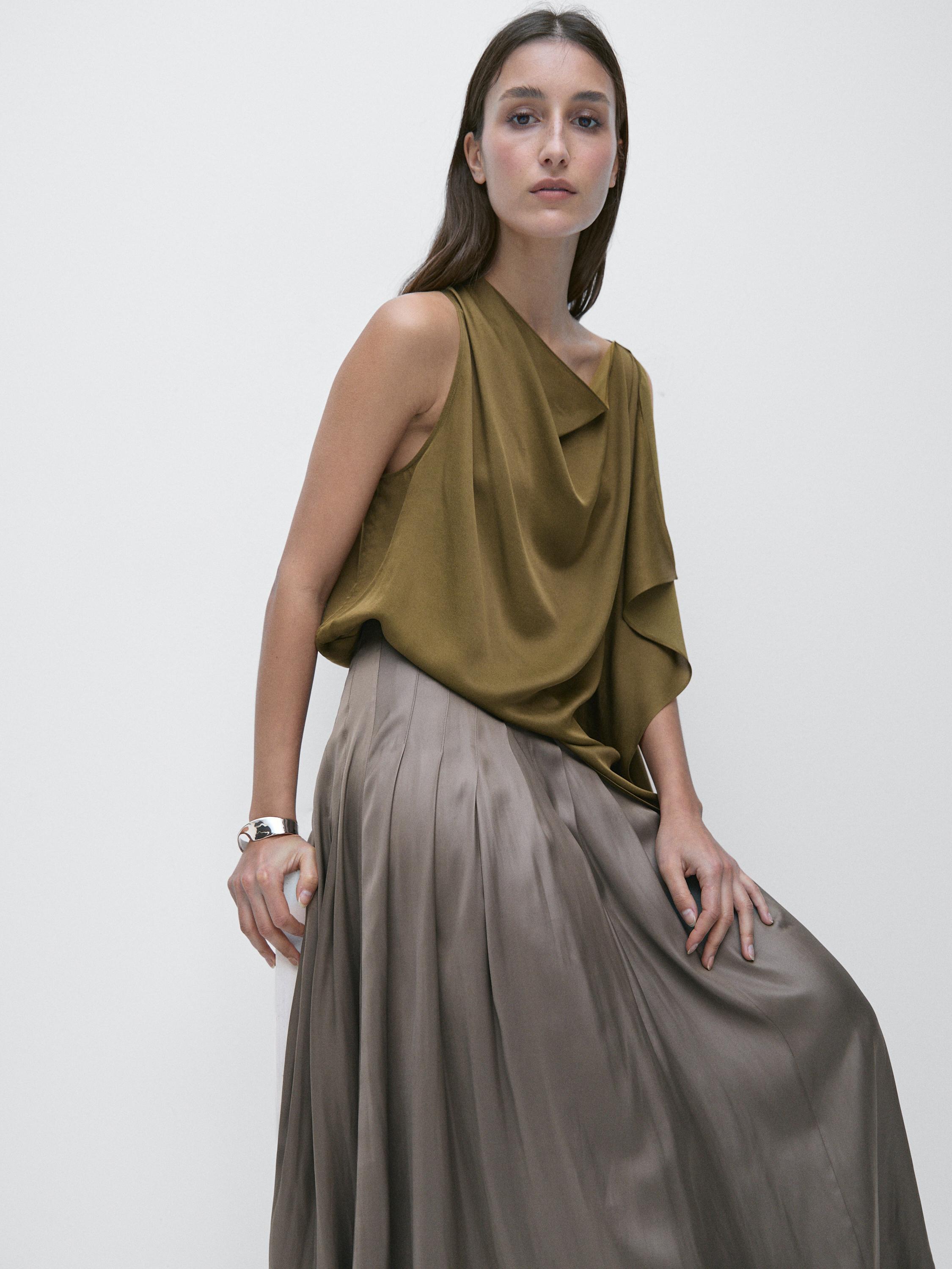 طقم بلوزة زيتوني بلا أكمام مع درابيه وتنورة ميدي رمادية بكسرات.