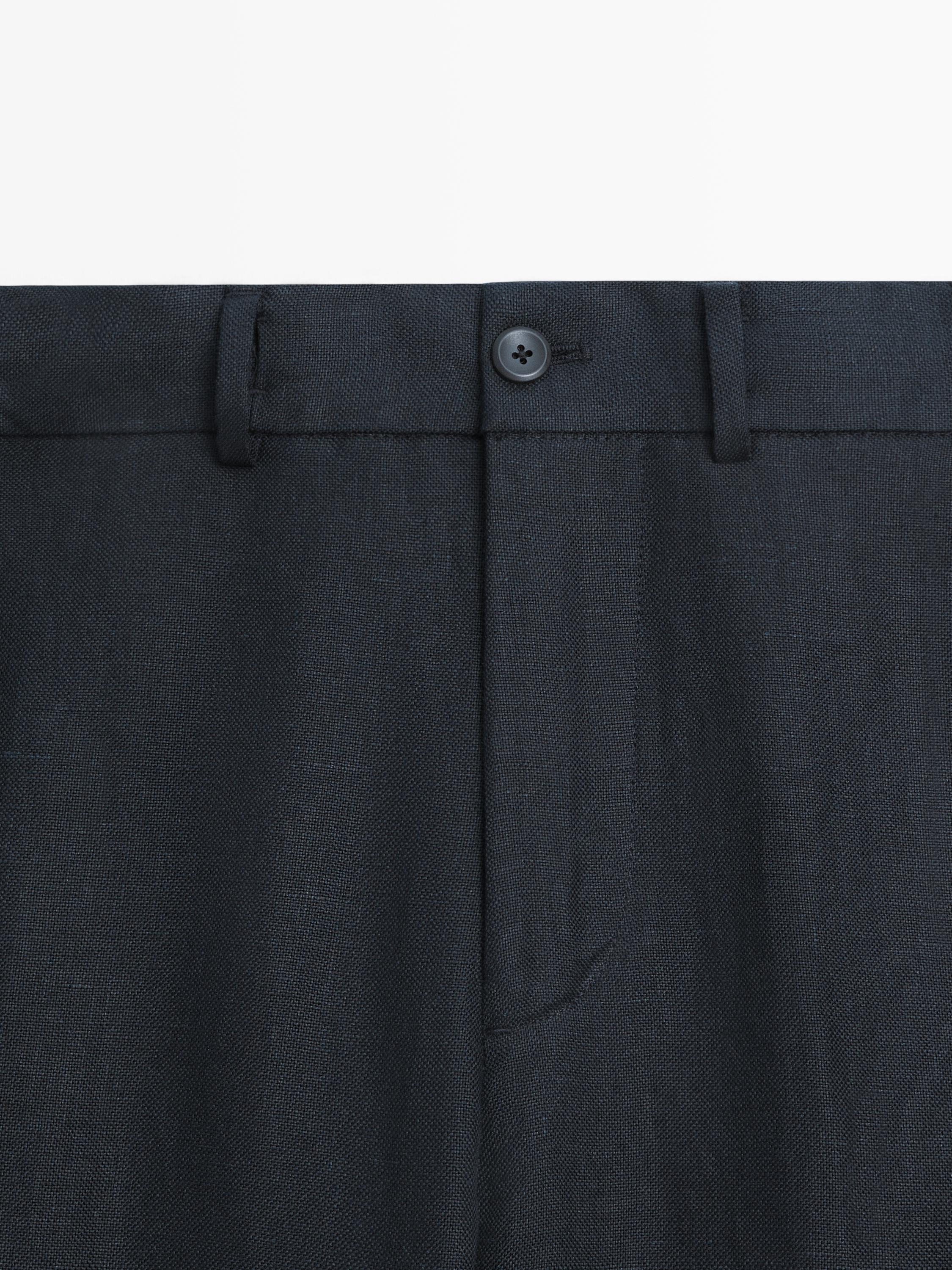 "Mittlere Einstellung der Taille einer tiefblauen Hose mit Knopfverschluss vorne und Gürtelschlaufen."