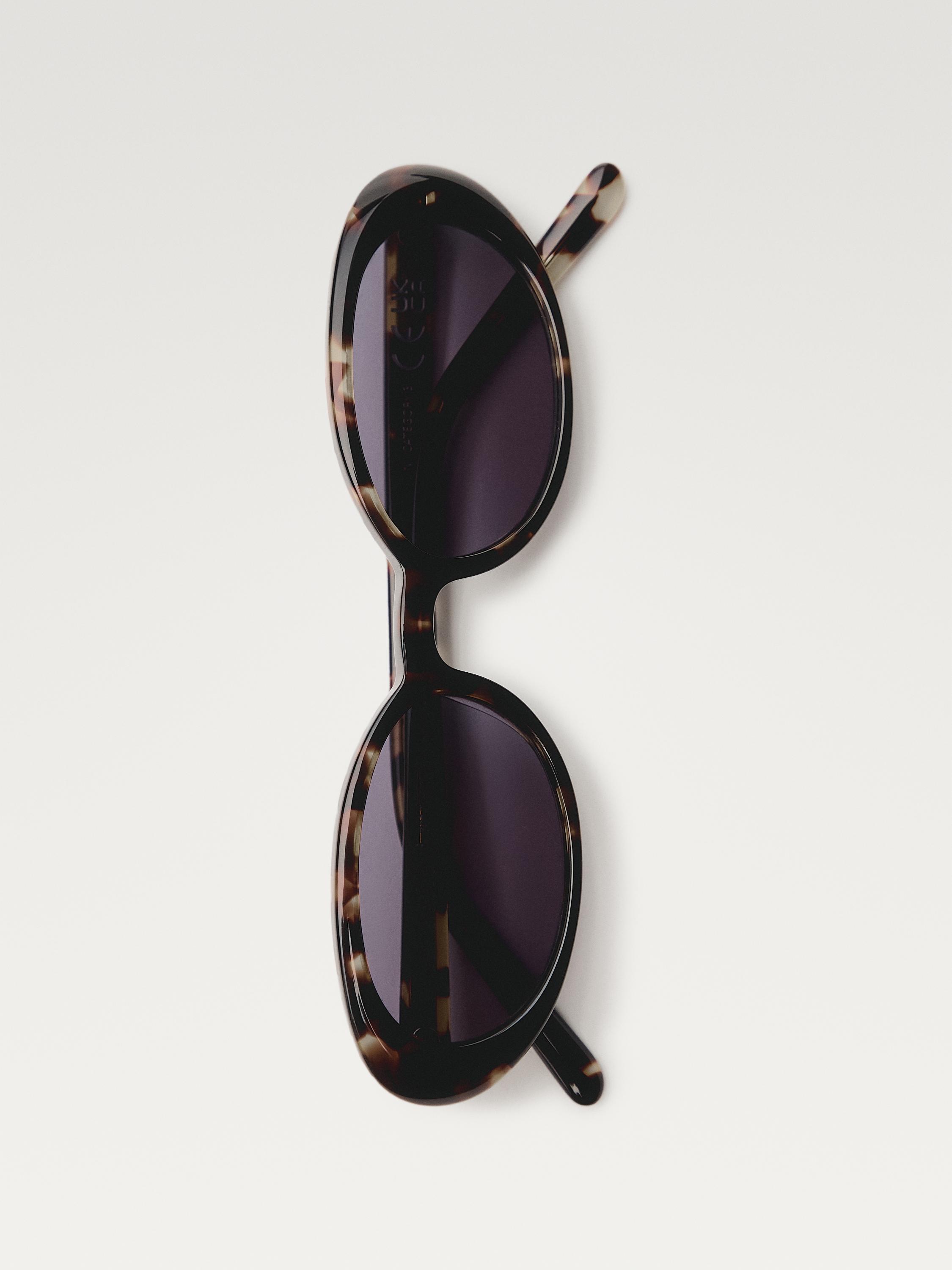 Vista frontale di occhiali da sole marroni con montatura ovale e aste maculate.