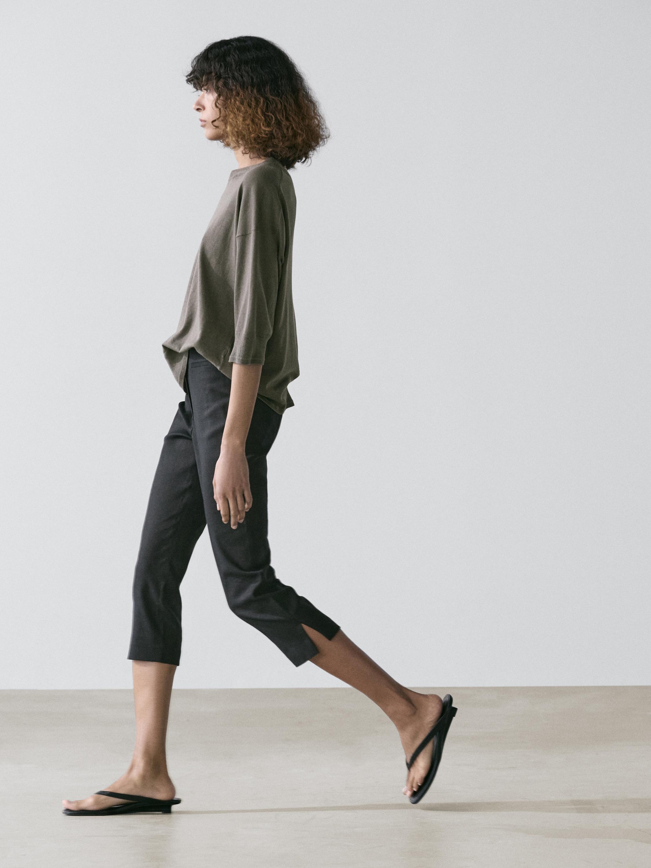 Conjunto de suéter café topo de manga corta y pantalones capri negros con aberturas laterales.