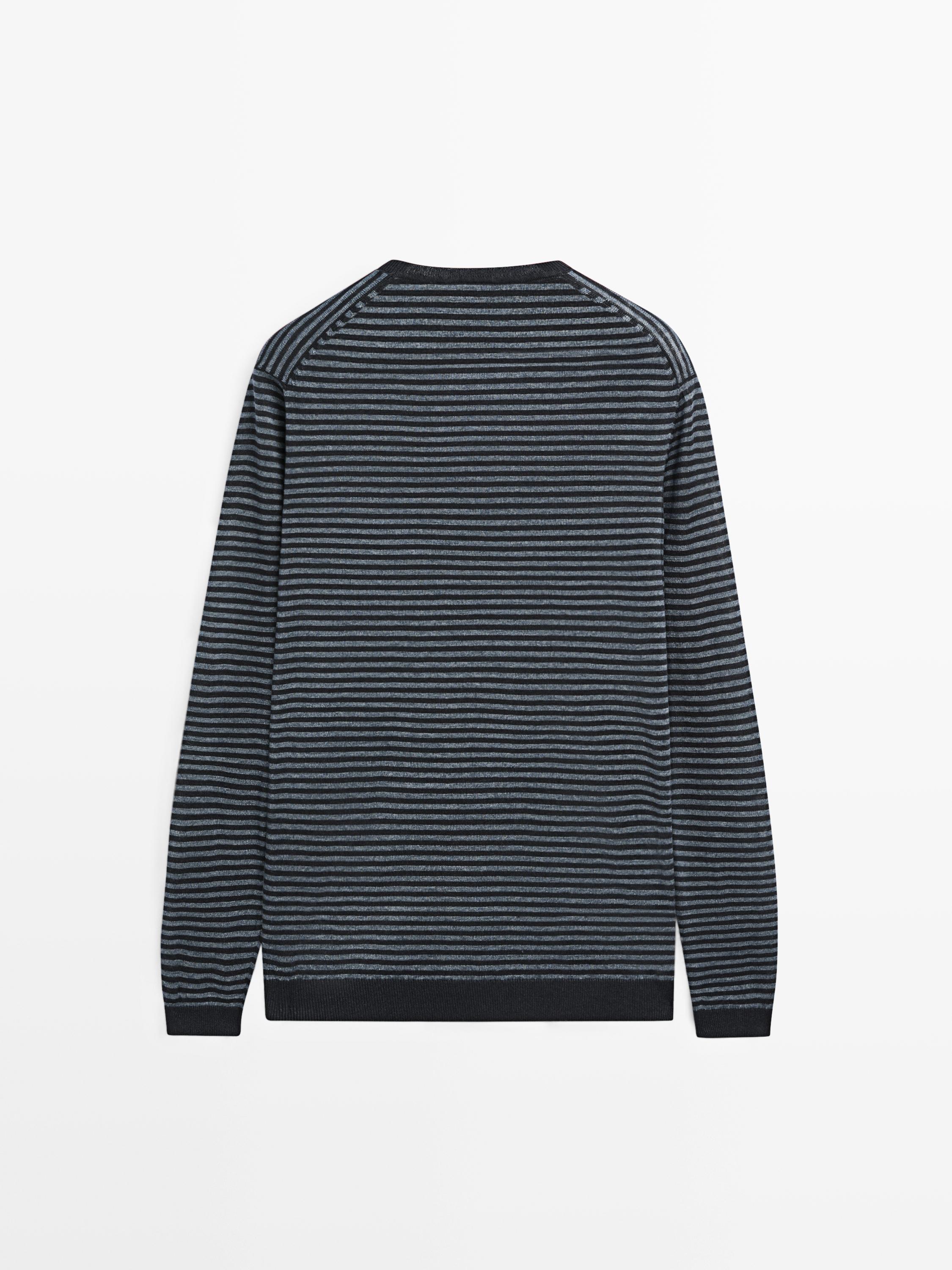 Vista posterior de un suéter azul marino con rayas horizontales grises y mangas largas.
