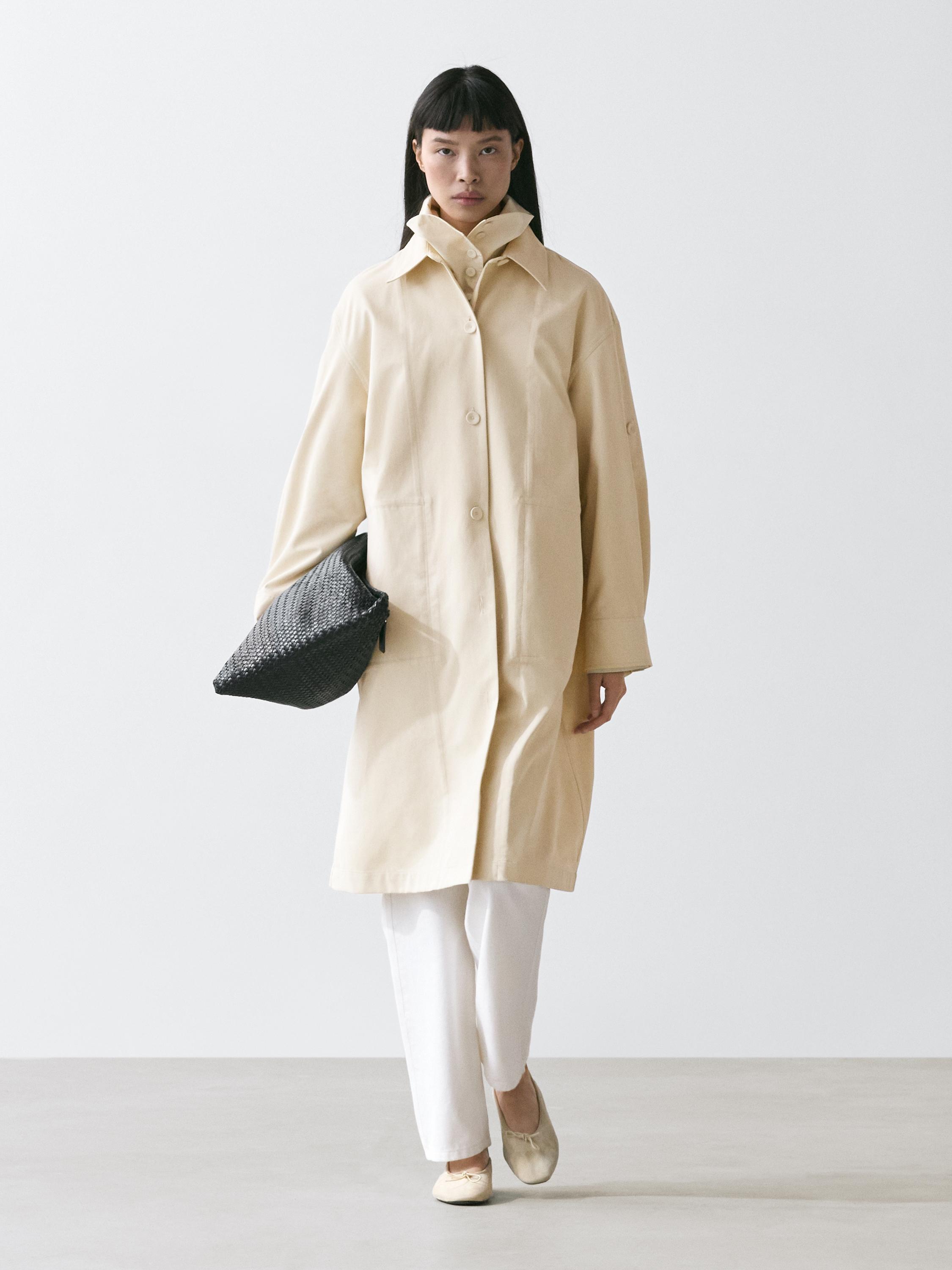 Light yellow trench coat set with buttons and roll-up sleeves, white pants, and beige shoes.