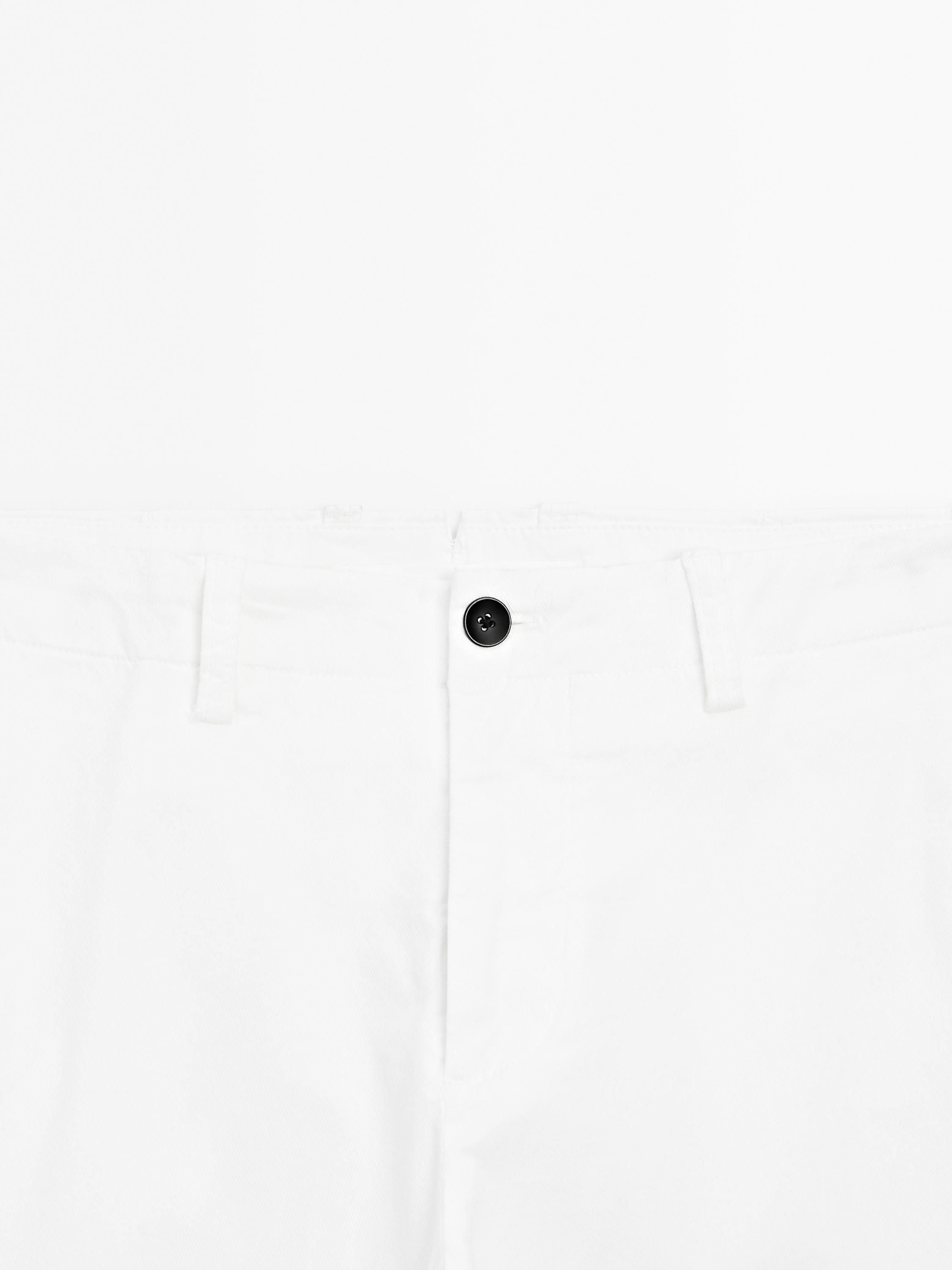 Κοντινό πλάνο της μέσης ενός λευκού παντελονιού με μαύρο κουμπί και θηλιές για ζώνη.