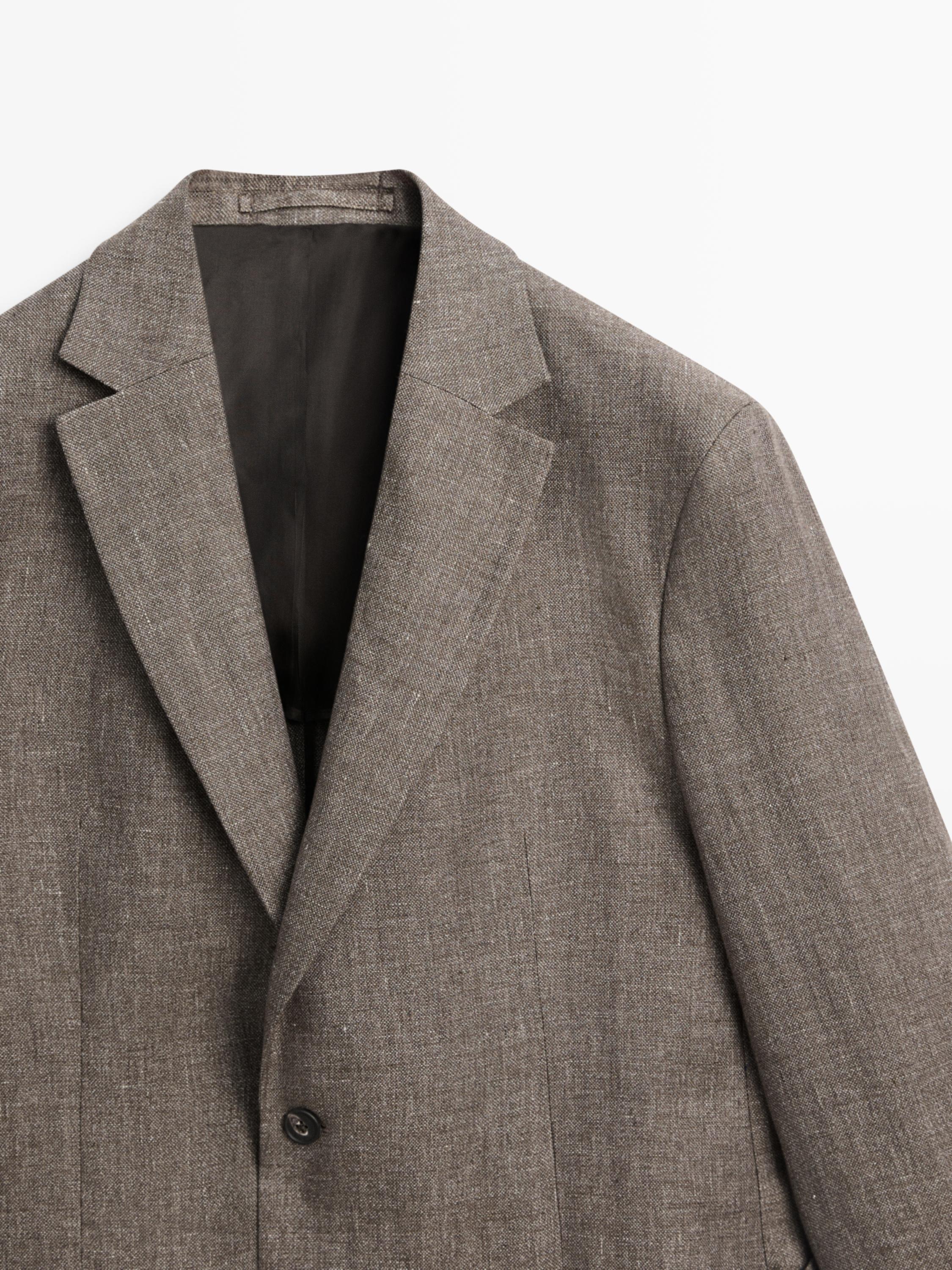 Plano médio de blazer bege com lapela de entalhe e fecho de um botão.