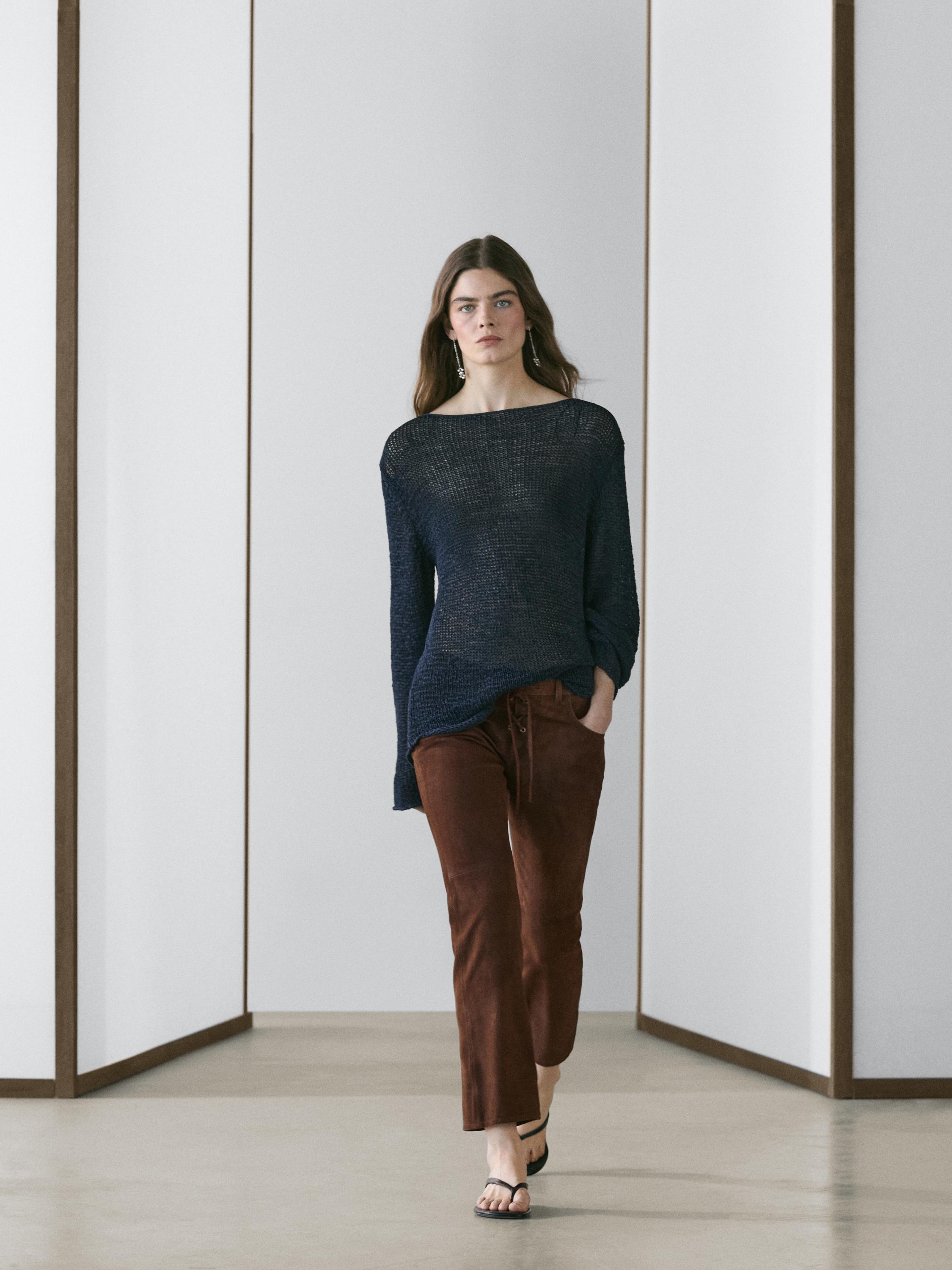 Conjunto de pantalón marrón con cordones y jersey azul marino de punto, sandalias negras.