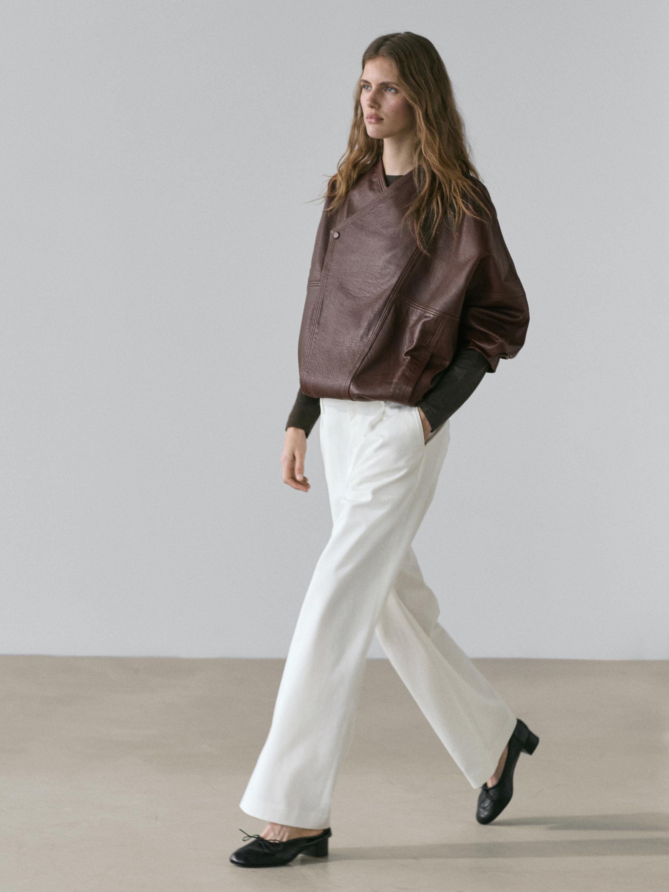 Brown jacket set with pockets and white pleated pants, black low-heeled shoes.
