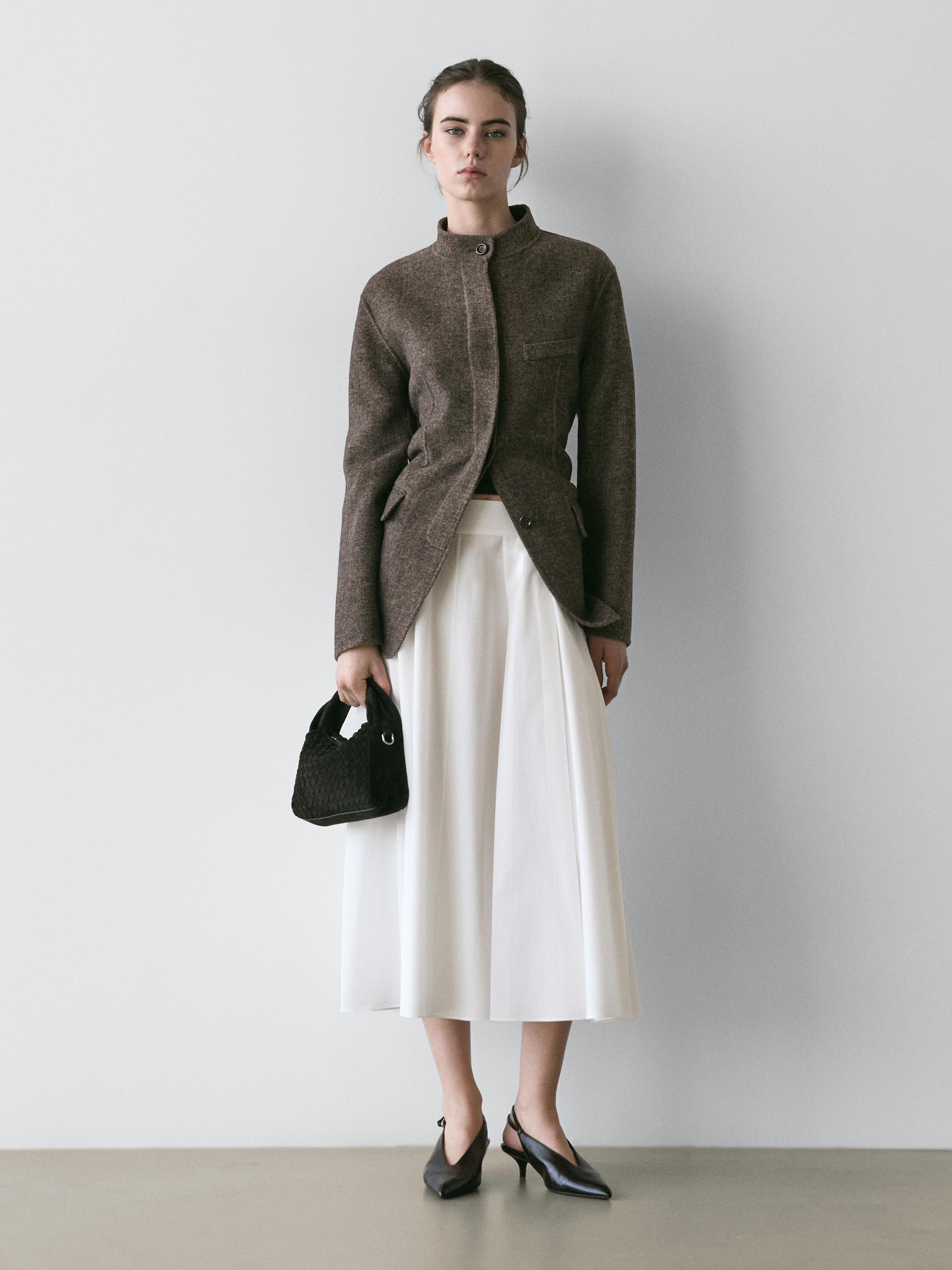 Conjunto de chaqueta marrón con bolsillos y falda midi blanca.