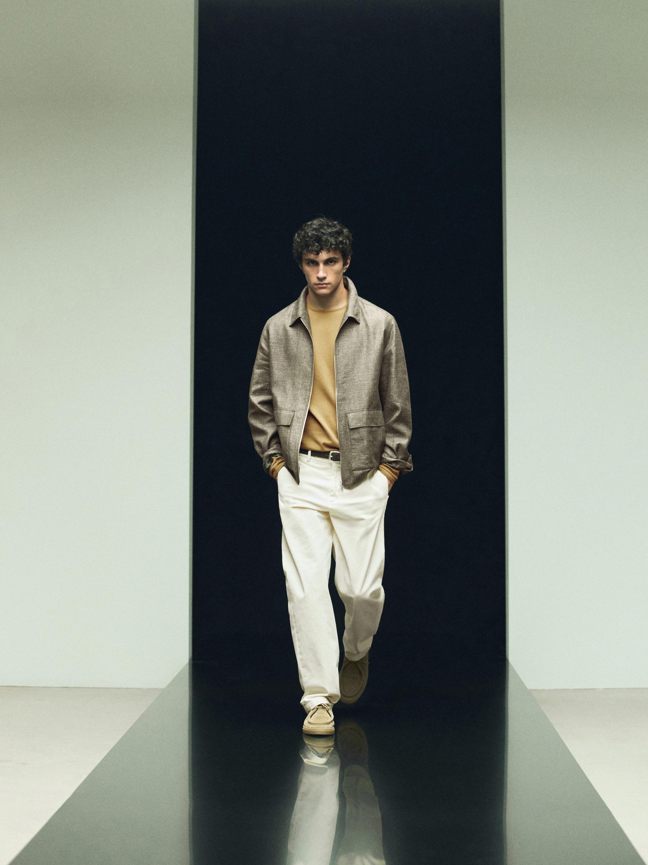 Conxunto de chaqueta curta marrón con petos, xersei beixe e pantalóns brancos.