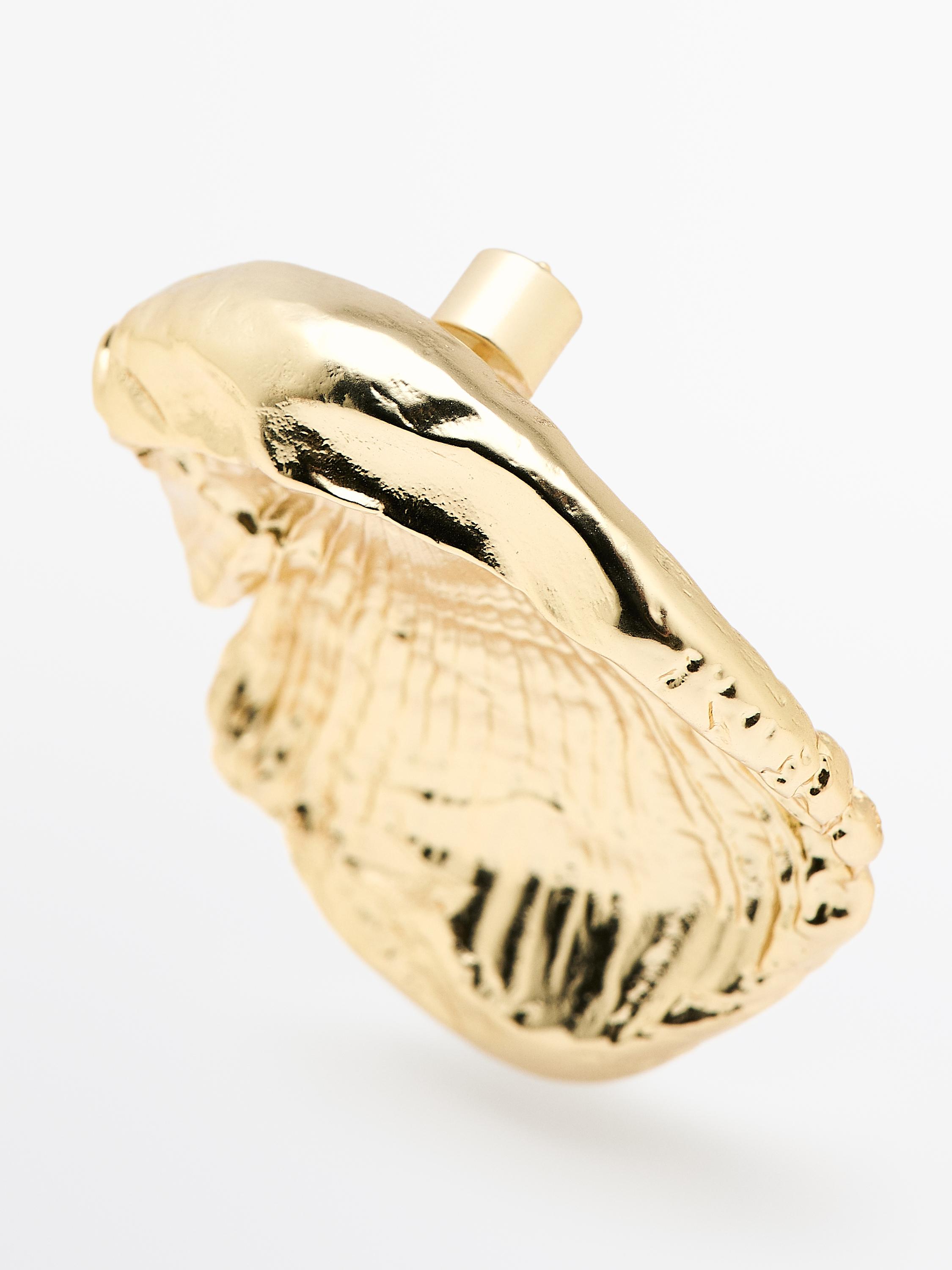 Gouden oorbel met schelpvorm, ruwe textuur en druksluiting.