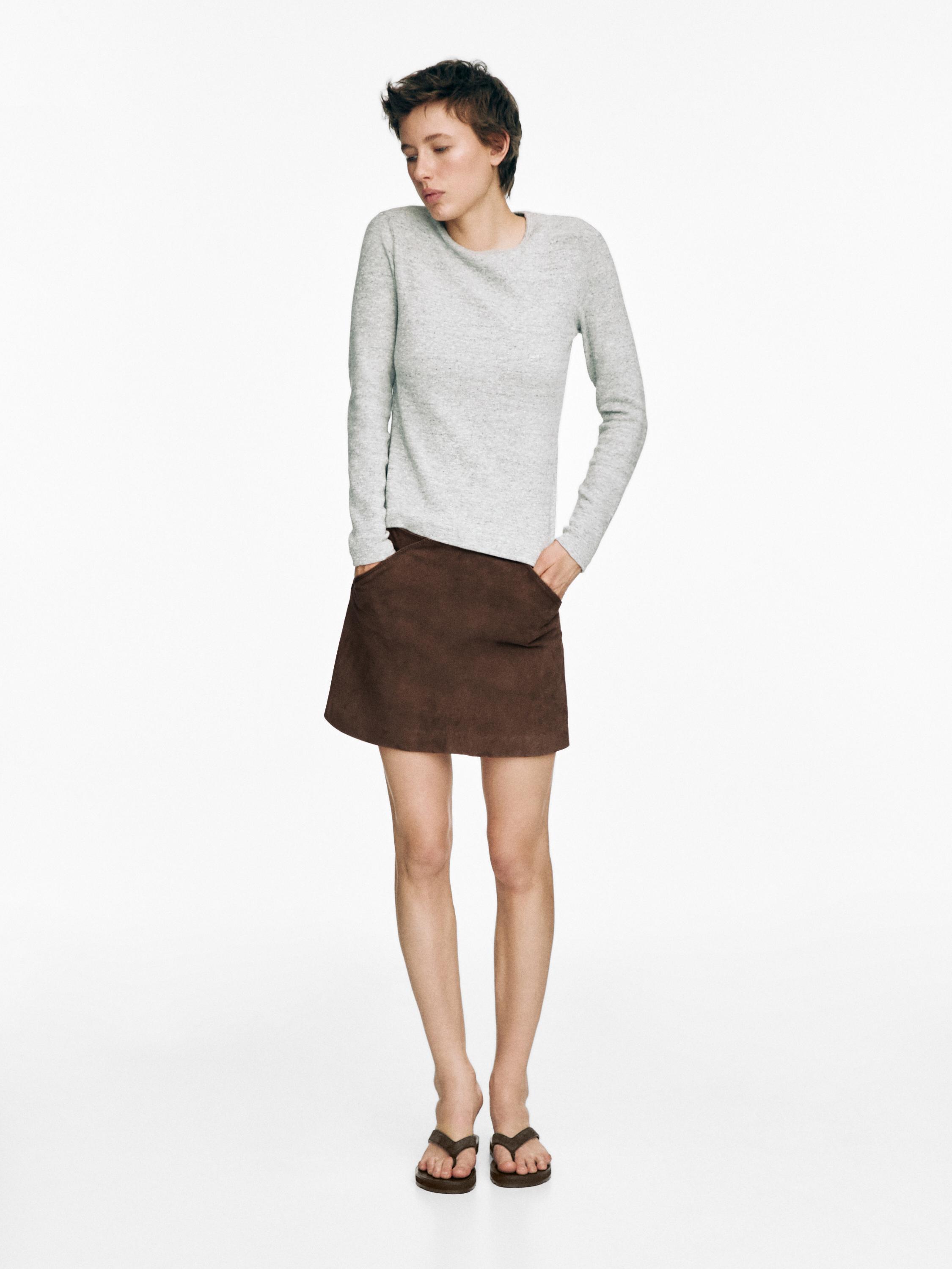 Conjunto de suéter gris, falda café con bolsillos laterales y sandalias planas cafés.