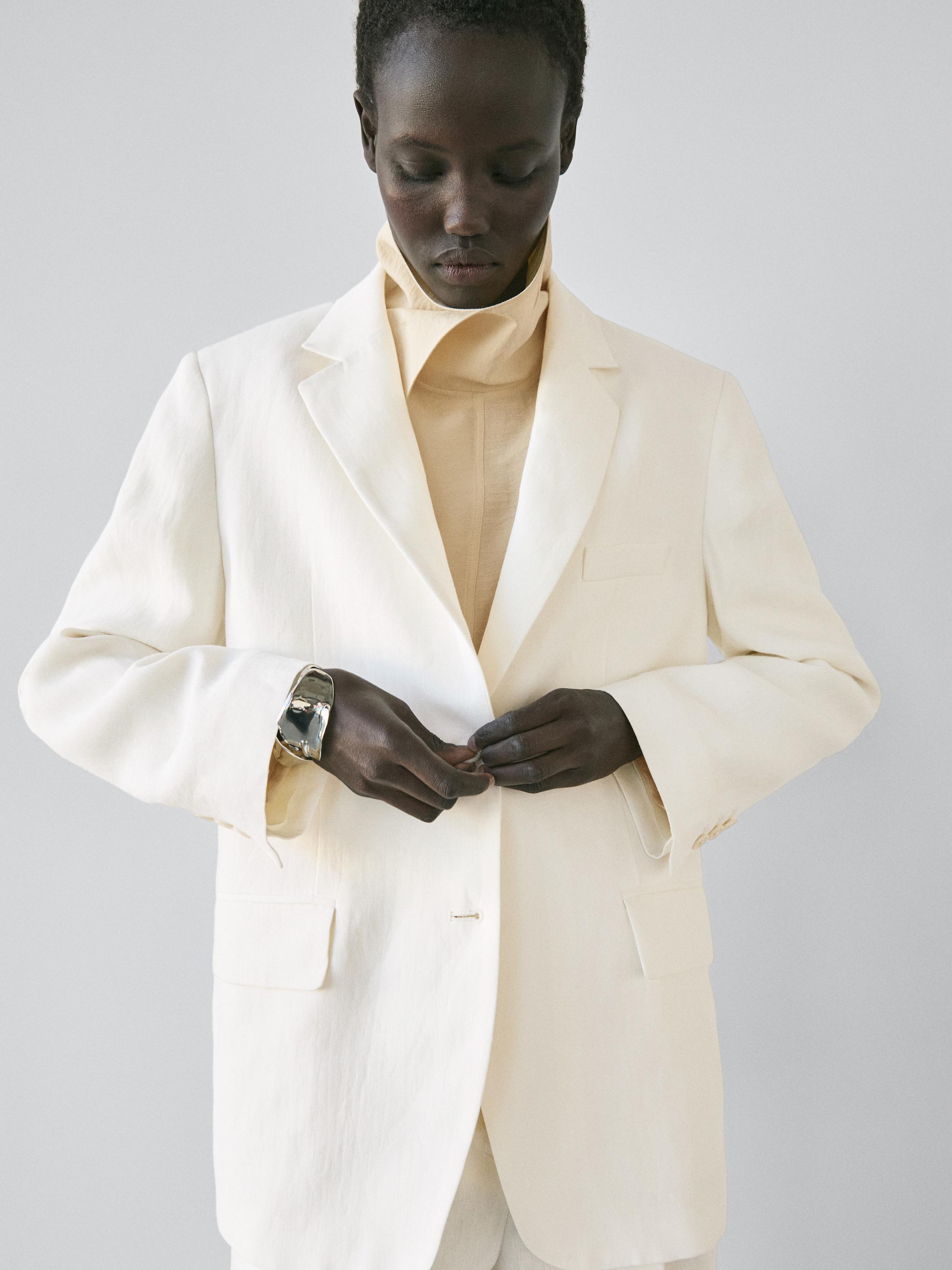 Blazer set with notched lapels and front flap pockets, over a beige turtleneck shirt.