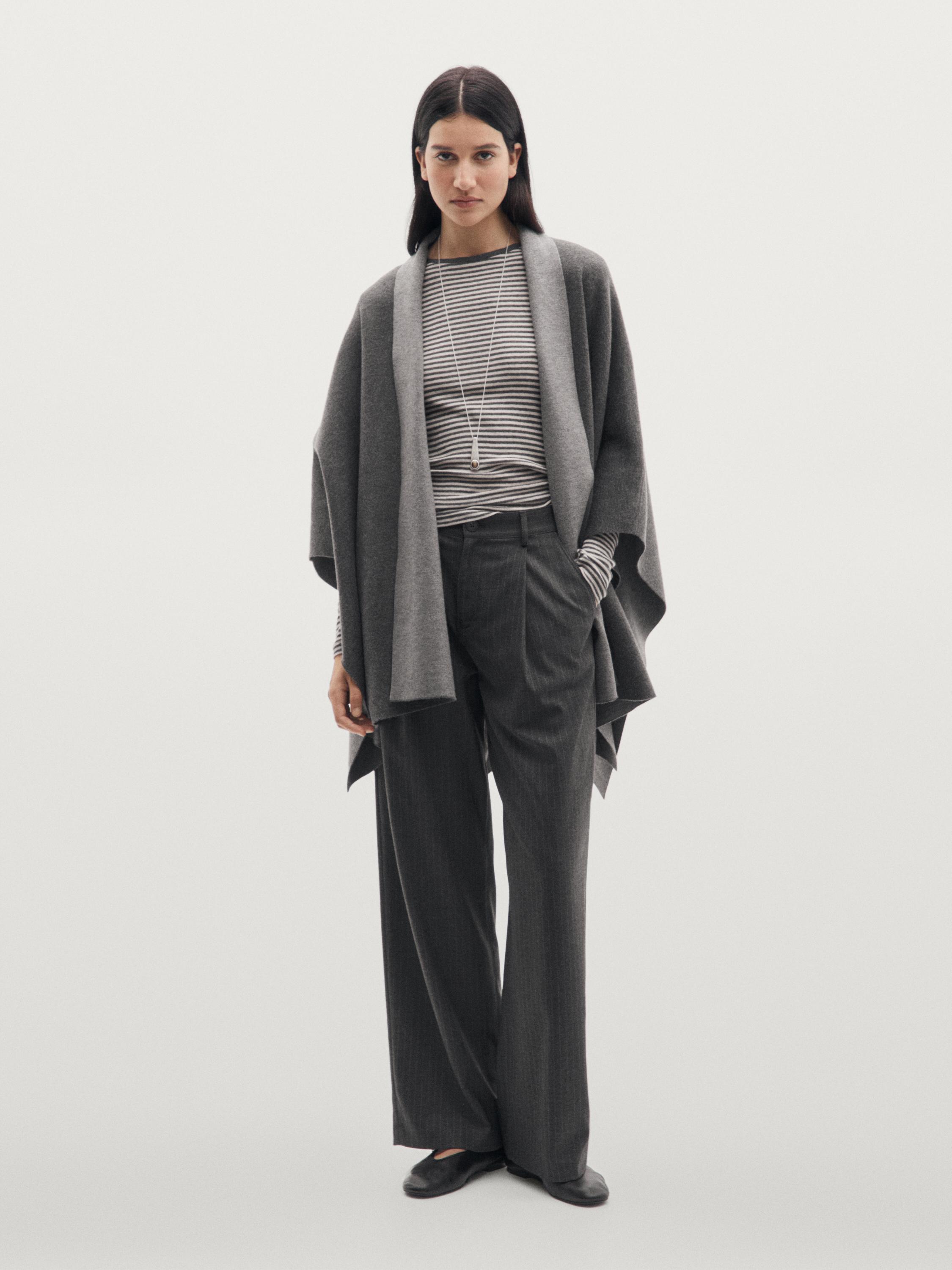 Ensemble composé d'une cape grise, d'un T-shirt rayé, d'un pantalon large gris et de chaussures noires.