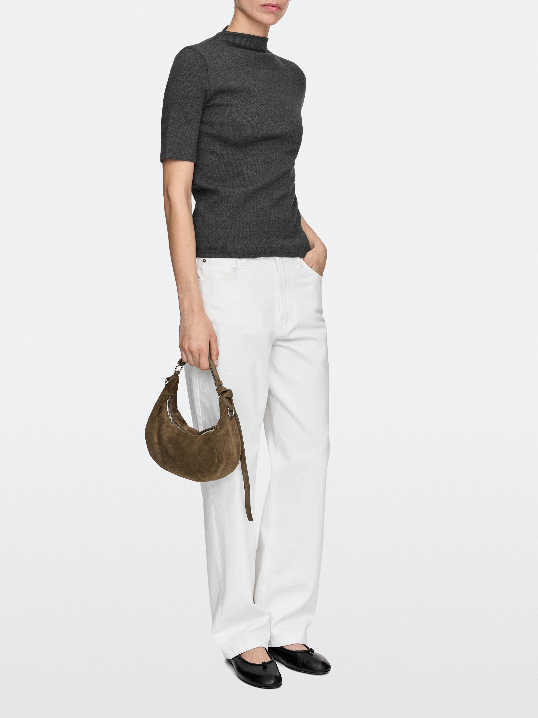 Kakikleurige handtas, witte wide-leg broek, grijs T-shirt met korte mouwen en zwarte schoenen.