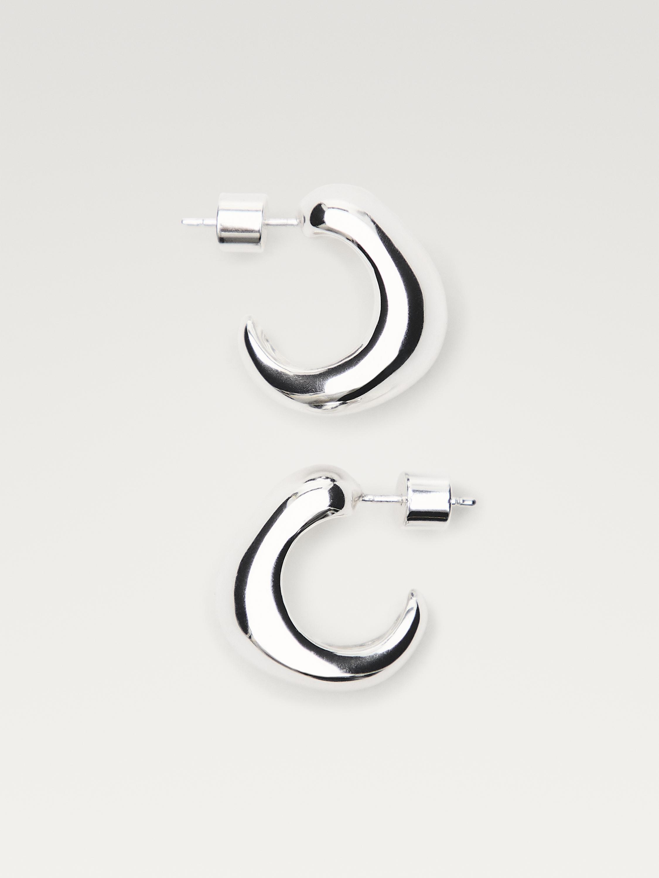 Gümüş rengi, kalın tasarımlı ve çıtçıt kapamalı halka küpelerin önden görünümü.