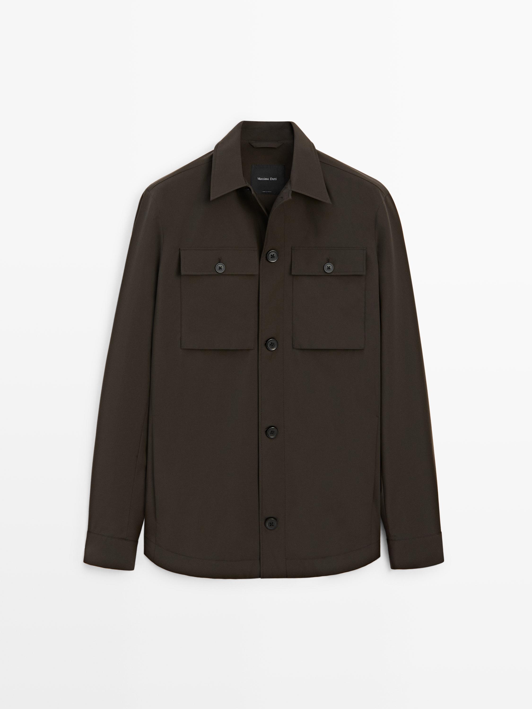 Vista frontal de casaco safari chocolate com bolsos frontais com aba e botões pretos.