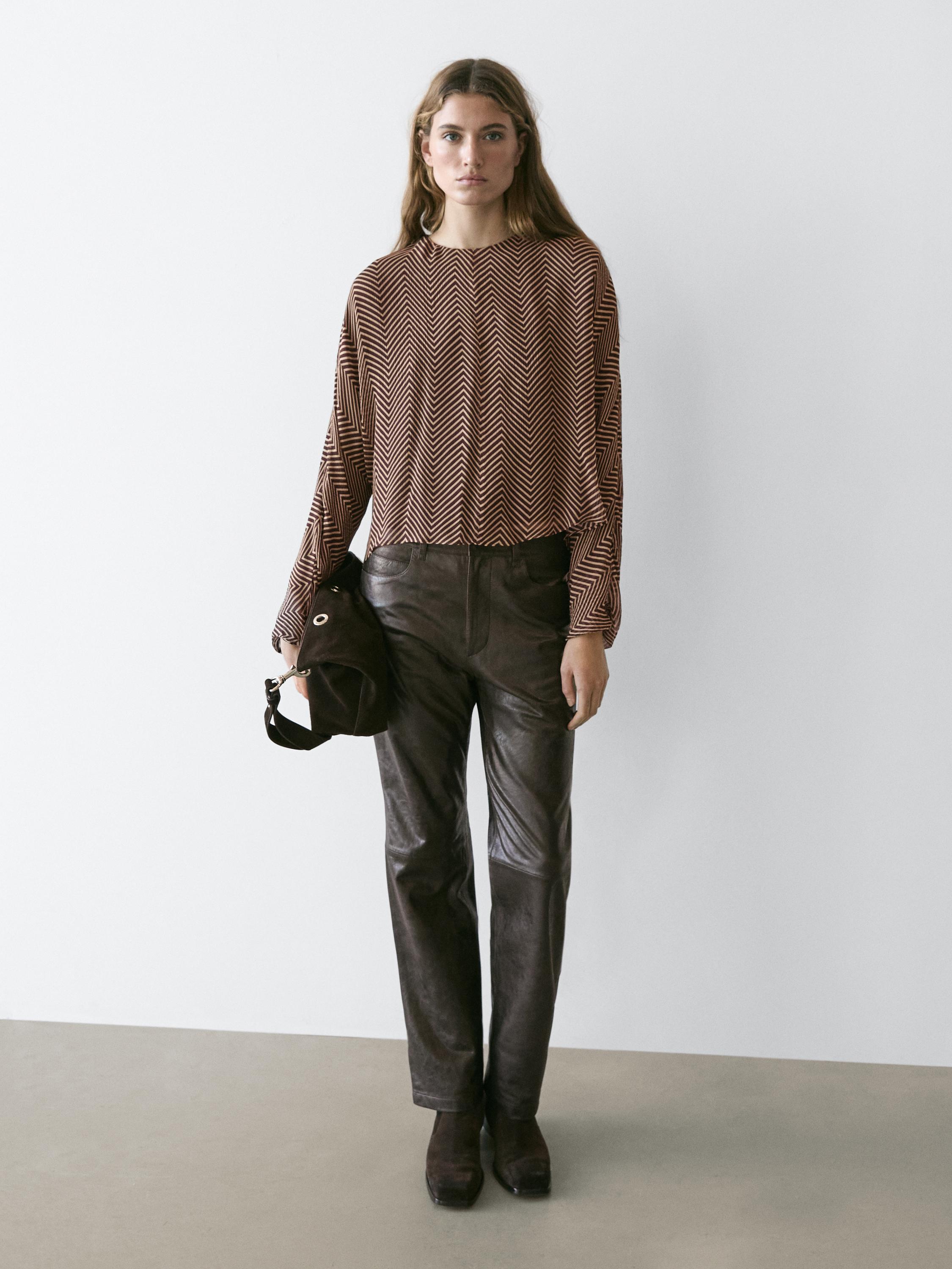 Conjunto de blusa burdeos con estampado geométrico y pantalones marrones.